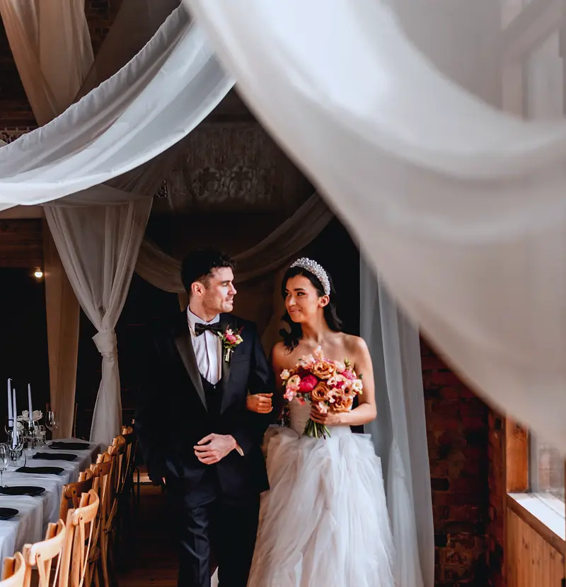 Newlyweds entering The Long Barn past draped fabric at Blackbrook Barns, Lichfield, Staffordshire