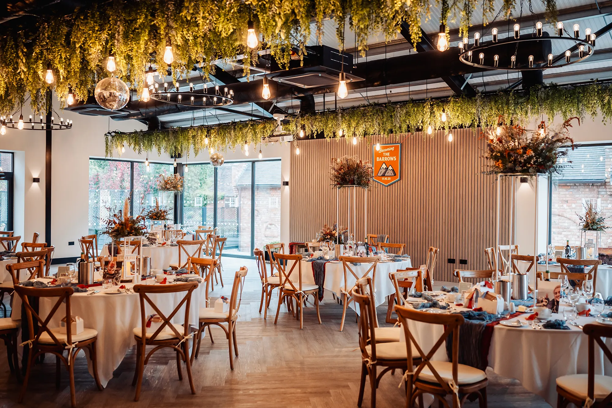 The Cow Shed set with round tables and autumnal florals at Blackbrook Barns, Lichfield, Staffordshire