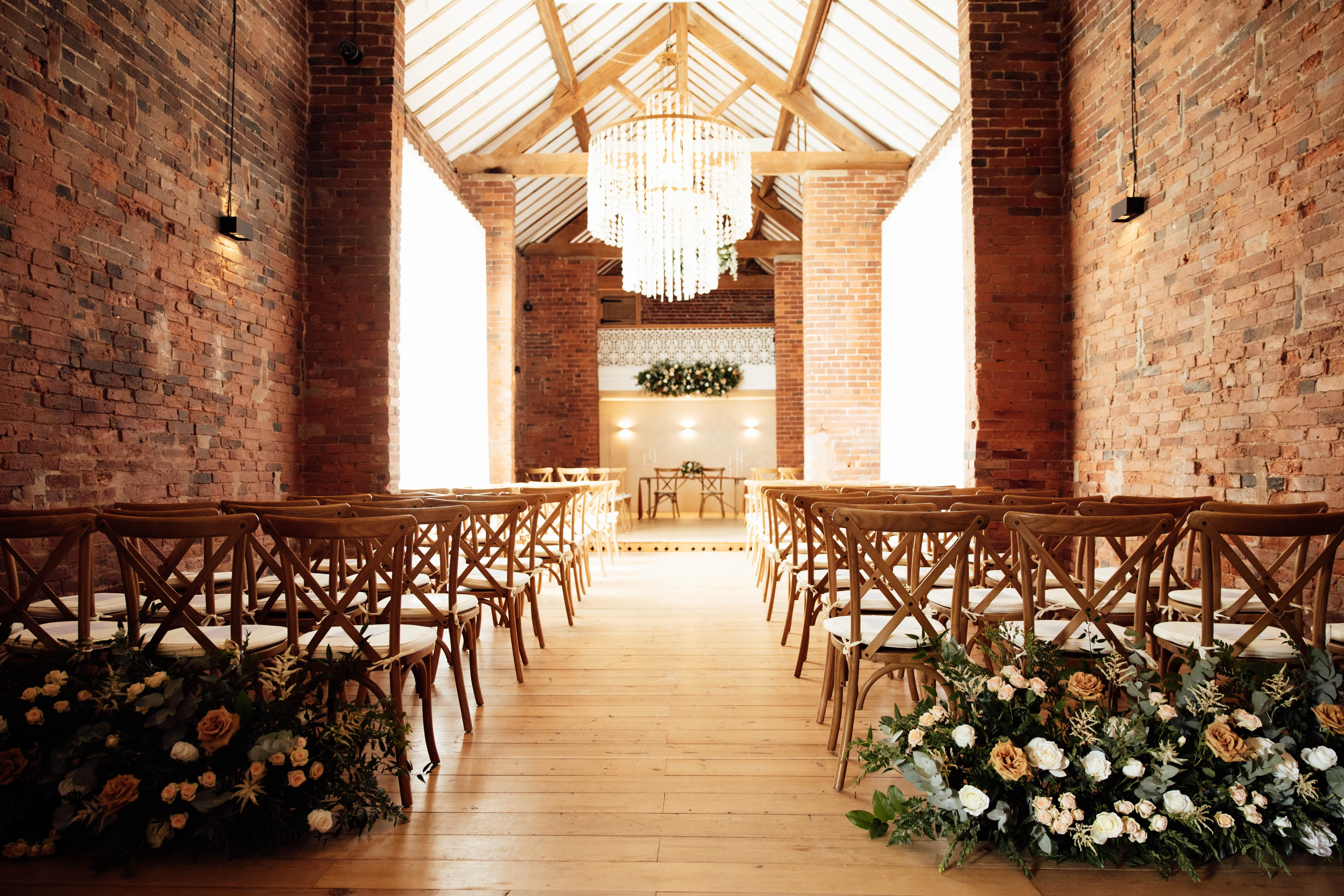 The Long Barn set for a ceremony with aisle florals at Blackbrook Barns, Lichfield, Staffordshire
