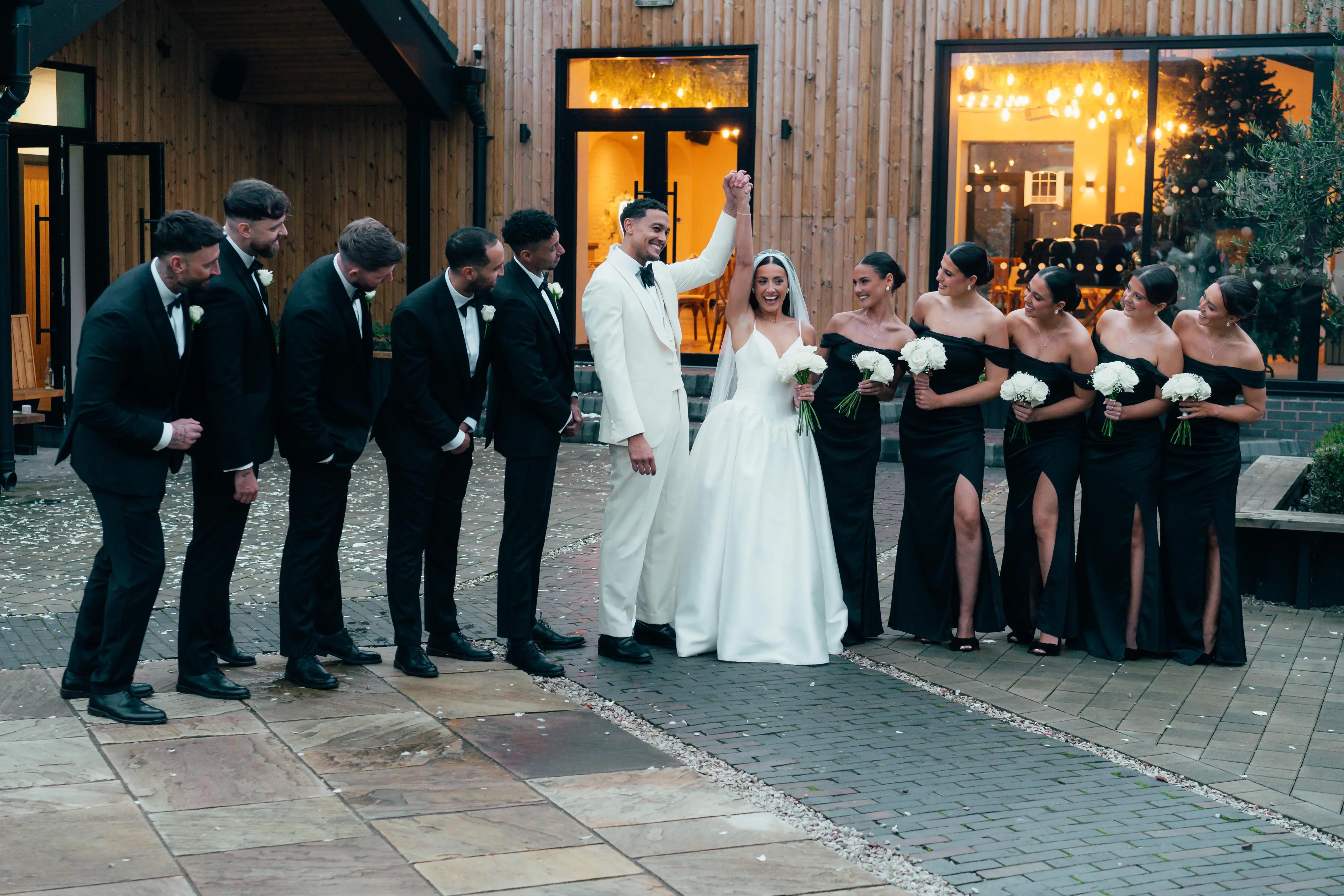 Newlyweds walking between their wedding party outside the venue at Blackbrook Barns, Lichfield, Staffordshire
