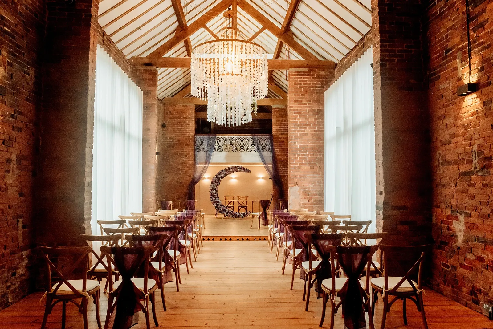 The Long Barn set for a ceremony with a crescent floral display at Blackbrook Barns, Lichfield, Staffordshire