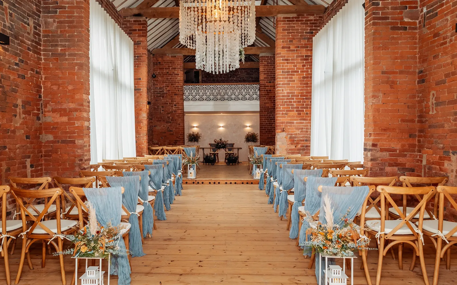 Ceremony aisle dressed with blue sashes and florals in The Long Barn at Blackbrook Barns, Lichfield, Staffordshire