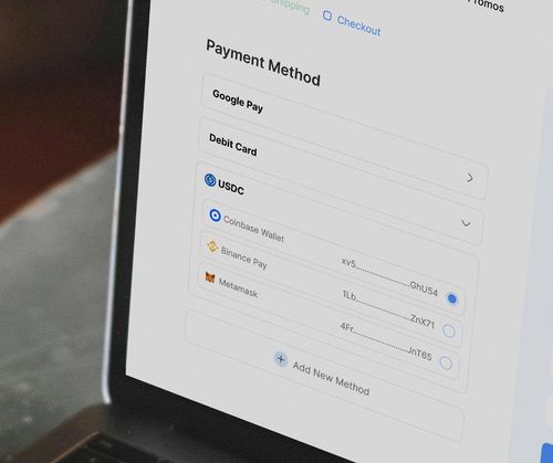 Laptop showing a payment screen with options to pay with USDC via a wallet