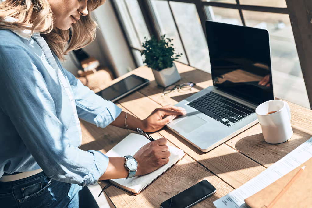Femme travaillant sur un ordinateur portable avec un café et des notes