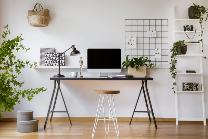 Loft home office under side dormer, sloped ceiling with skylight, floating desk, wooden shelves, and fitted drawers in white finish.