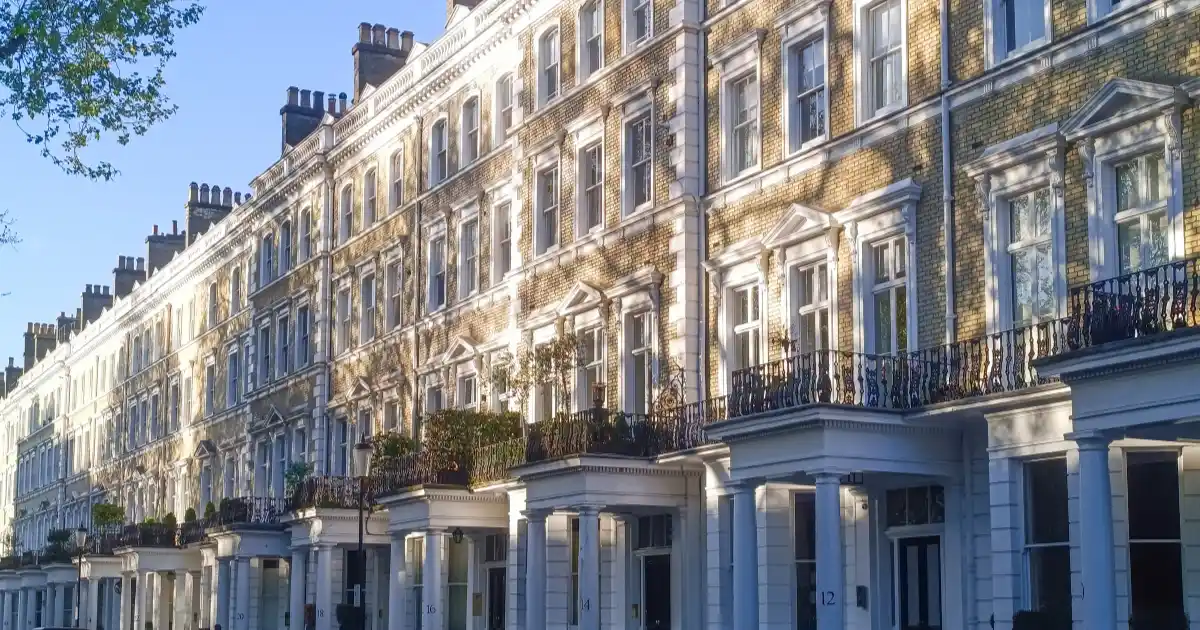 Sunlit row of Victorian terraced houses with white stone and yellow brick façades.