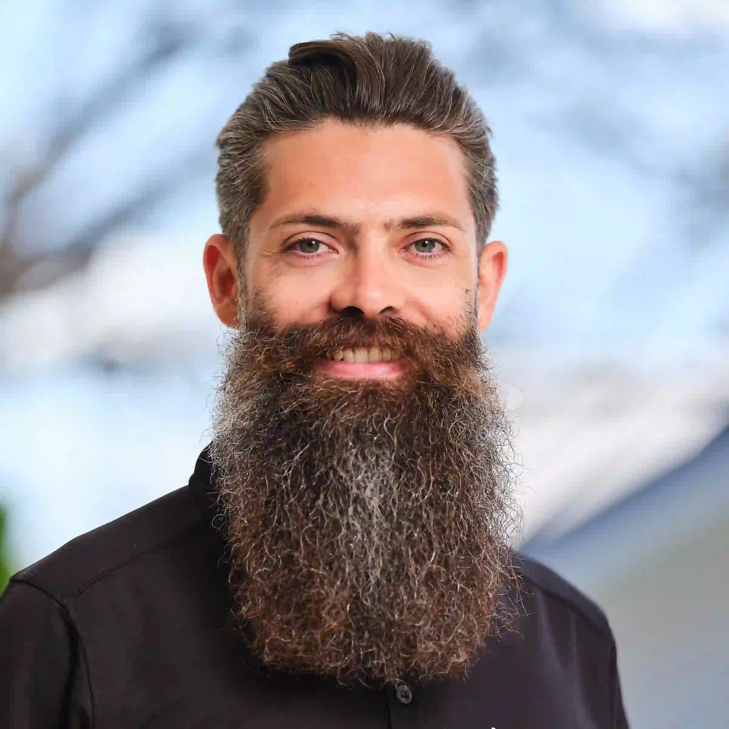David Green in a Green.com.au polo shirt standing against a background of sky and trees