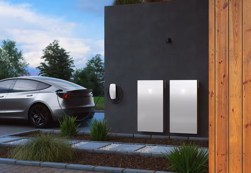 Tesla batteries installed on a Tesla home with a Tesla car charging in the driveway.