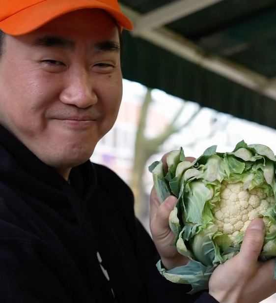 a korean man, holding cauliflower.