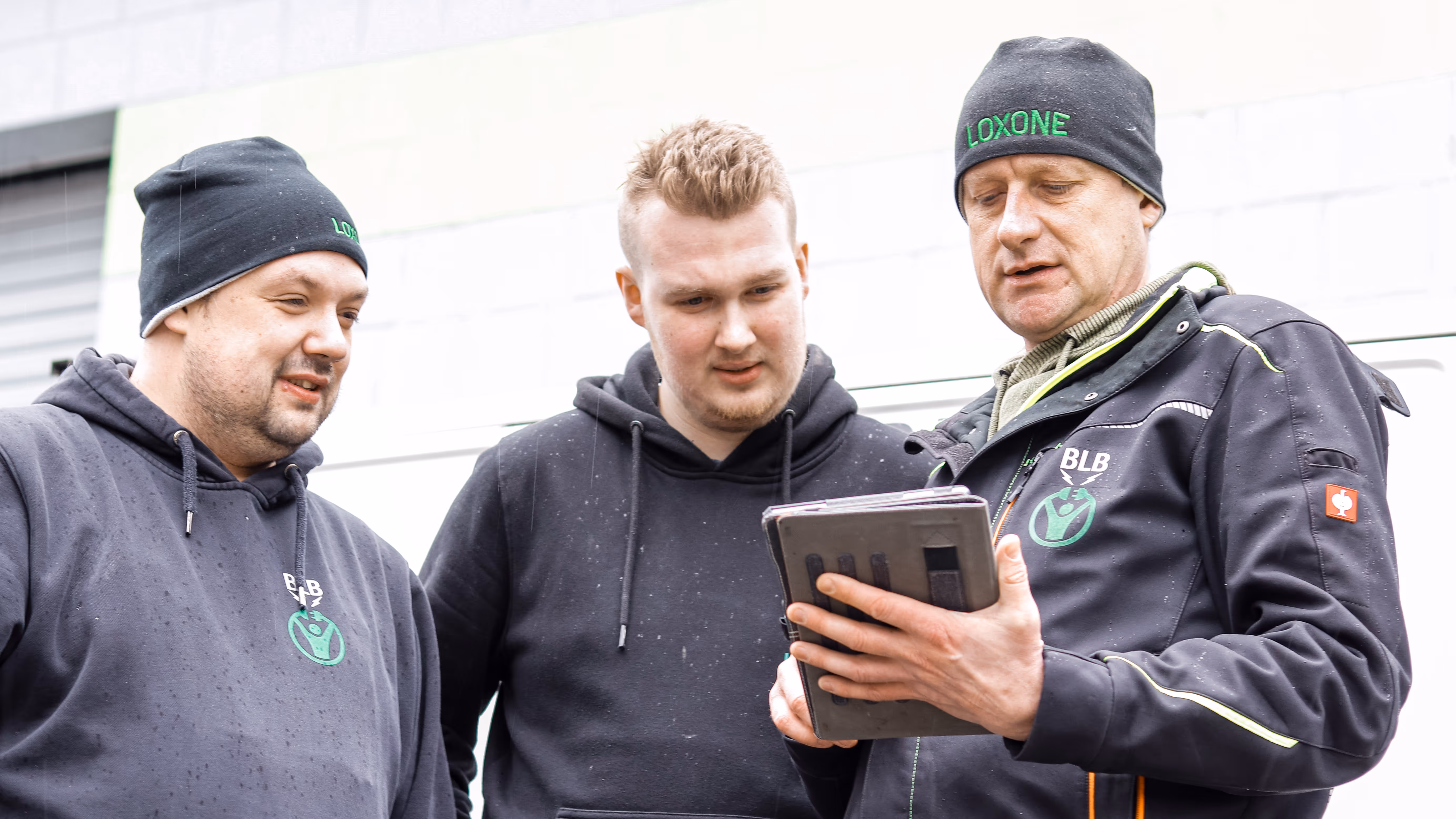 Drei Männer schauen in ein Tablet