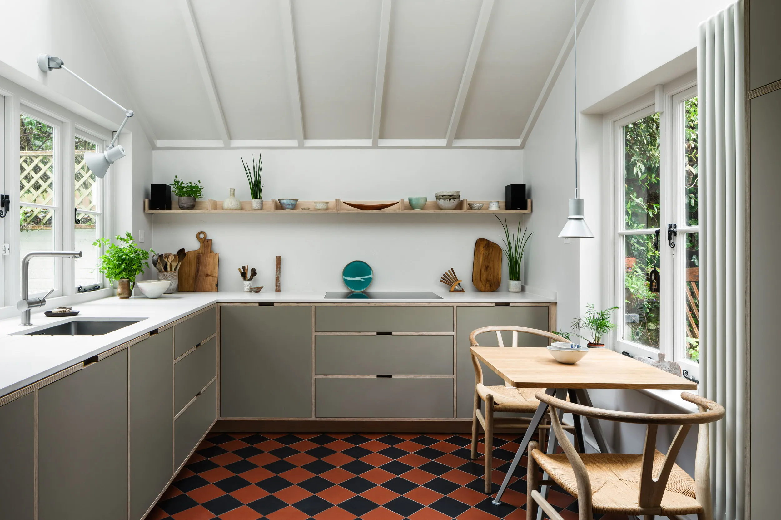 An ash-veneered birch plywood kitchen balancing contemporary lightness with the cottage’s terracotta chequerboard floor.ud