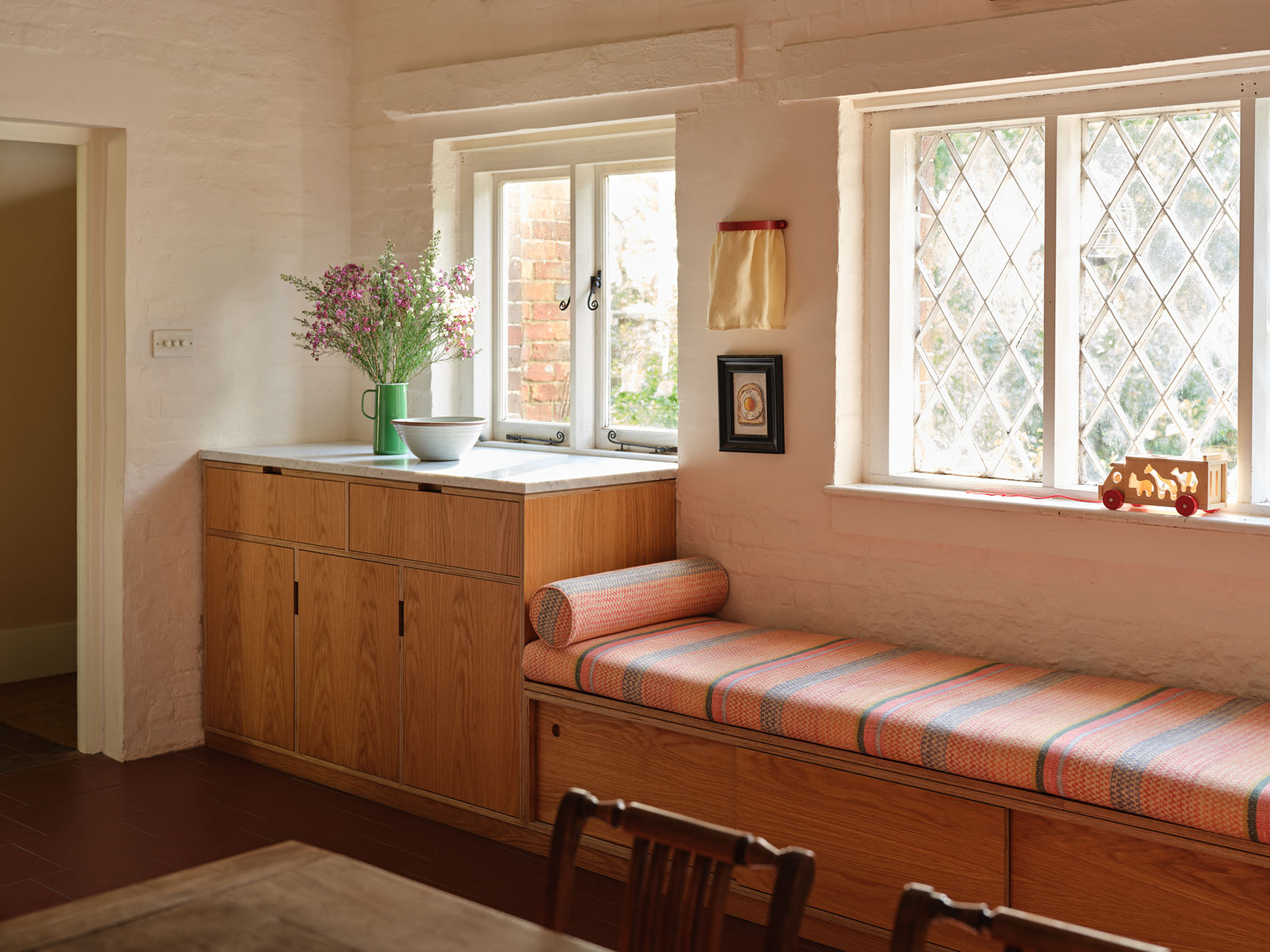 Bespoke oak cabinetry and built-in window seat by Uncommon Projects with marble worktop and heritage-style windows