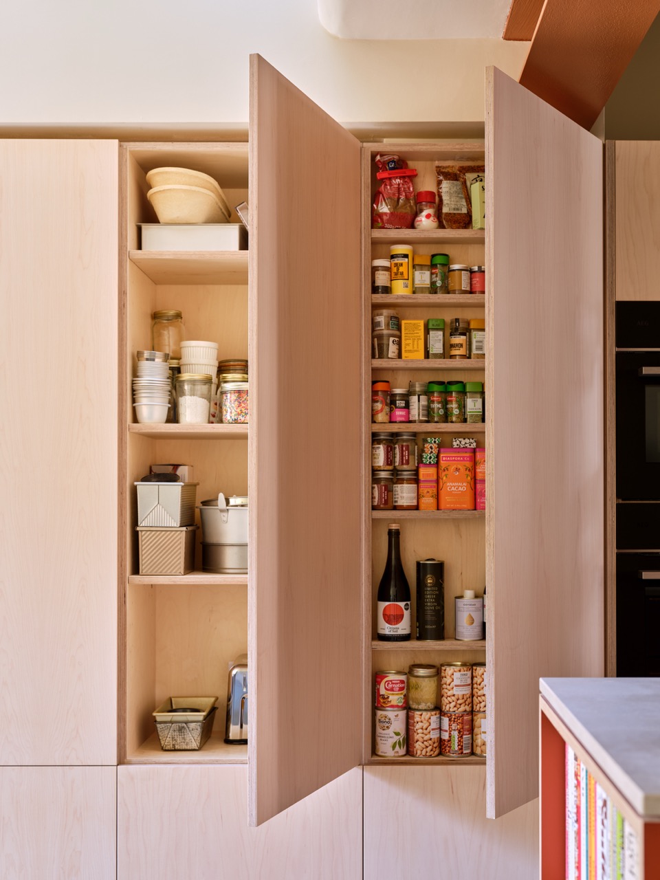 Bespoke pantry and spice storage in baker Edd Kimber’s Walthamstow kitchen, designed by Uncommon Projects with maple veneer plywood cabinetry and tailored shelving for ingredients and baking essentials.
