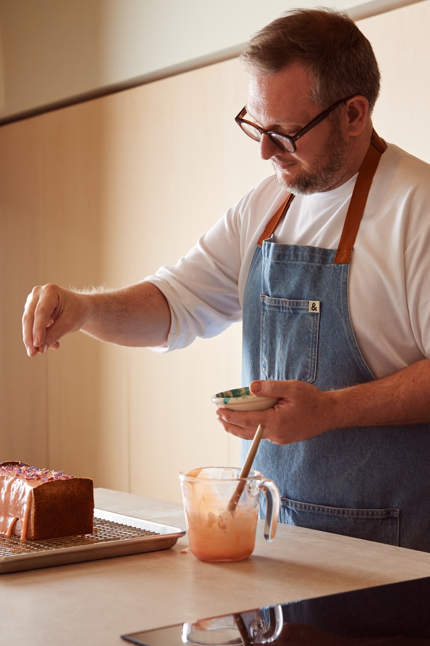 Baker and author Edd Kimber icing a cake at the island in his bespoke Uncommon Projects kitchen in Walthamstow, designed to support his baking, photography and recipe development.