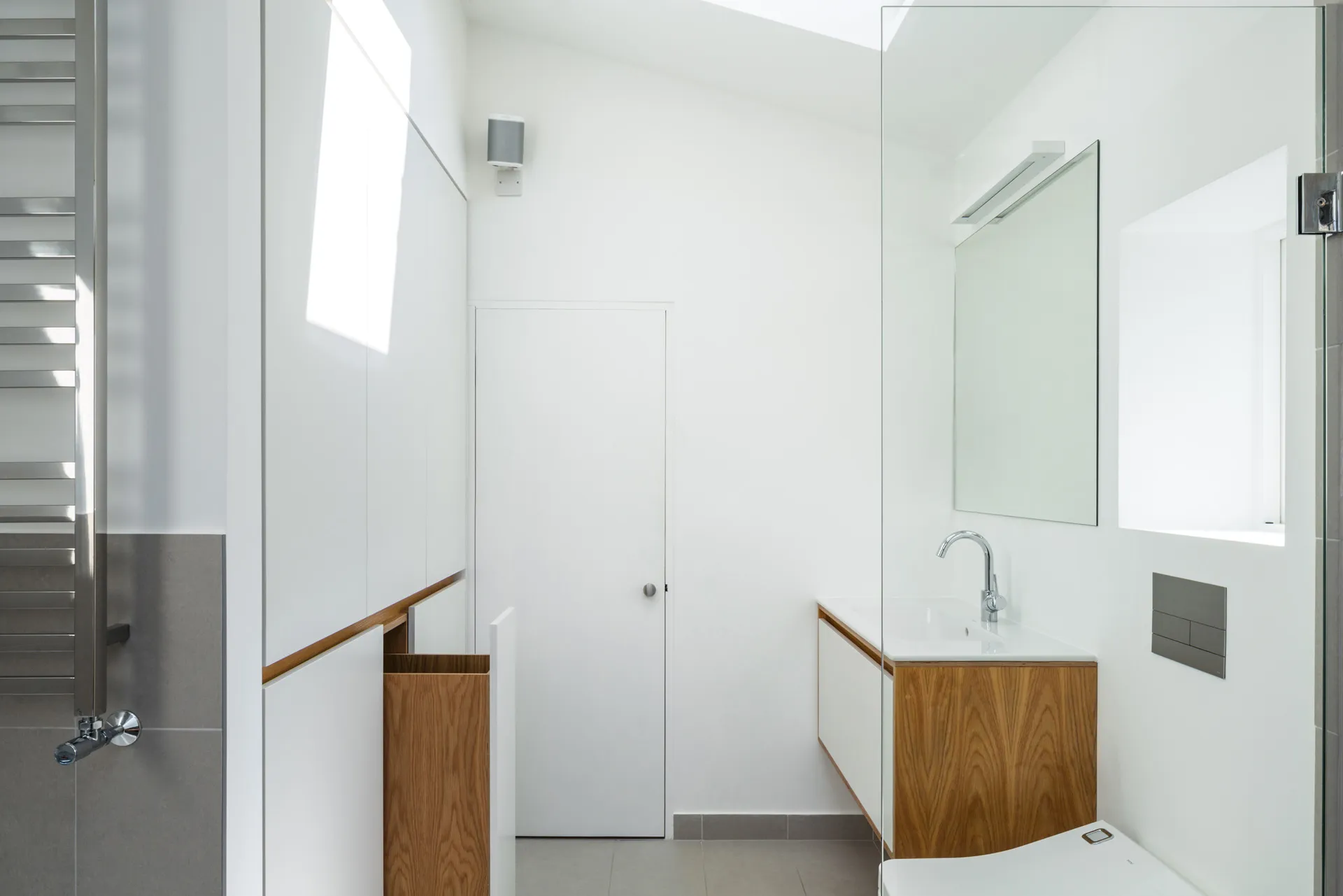 This minimal white bathroom features storage and wall mounted vanity unit in our ‘Linear’ style.