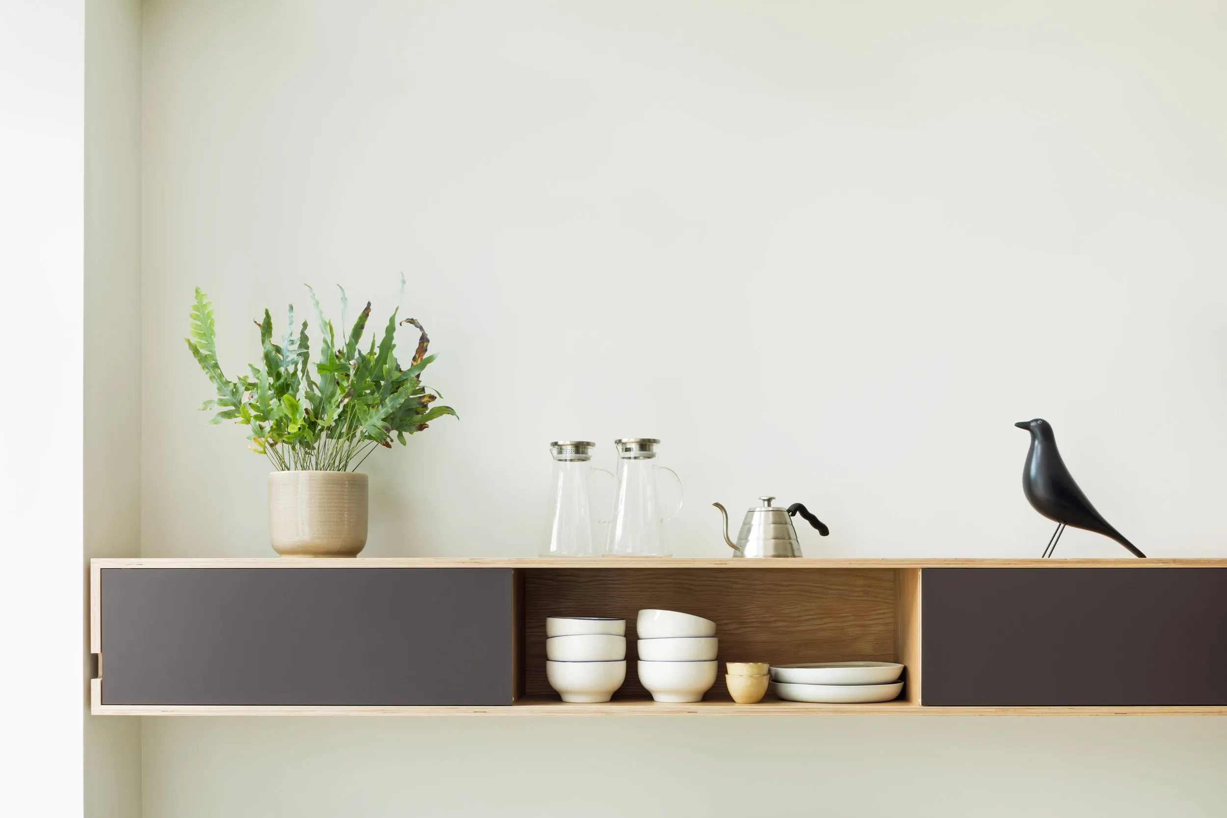 Narrow sliding door wall cabinet with plant and bird on top