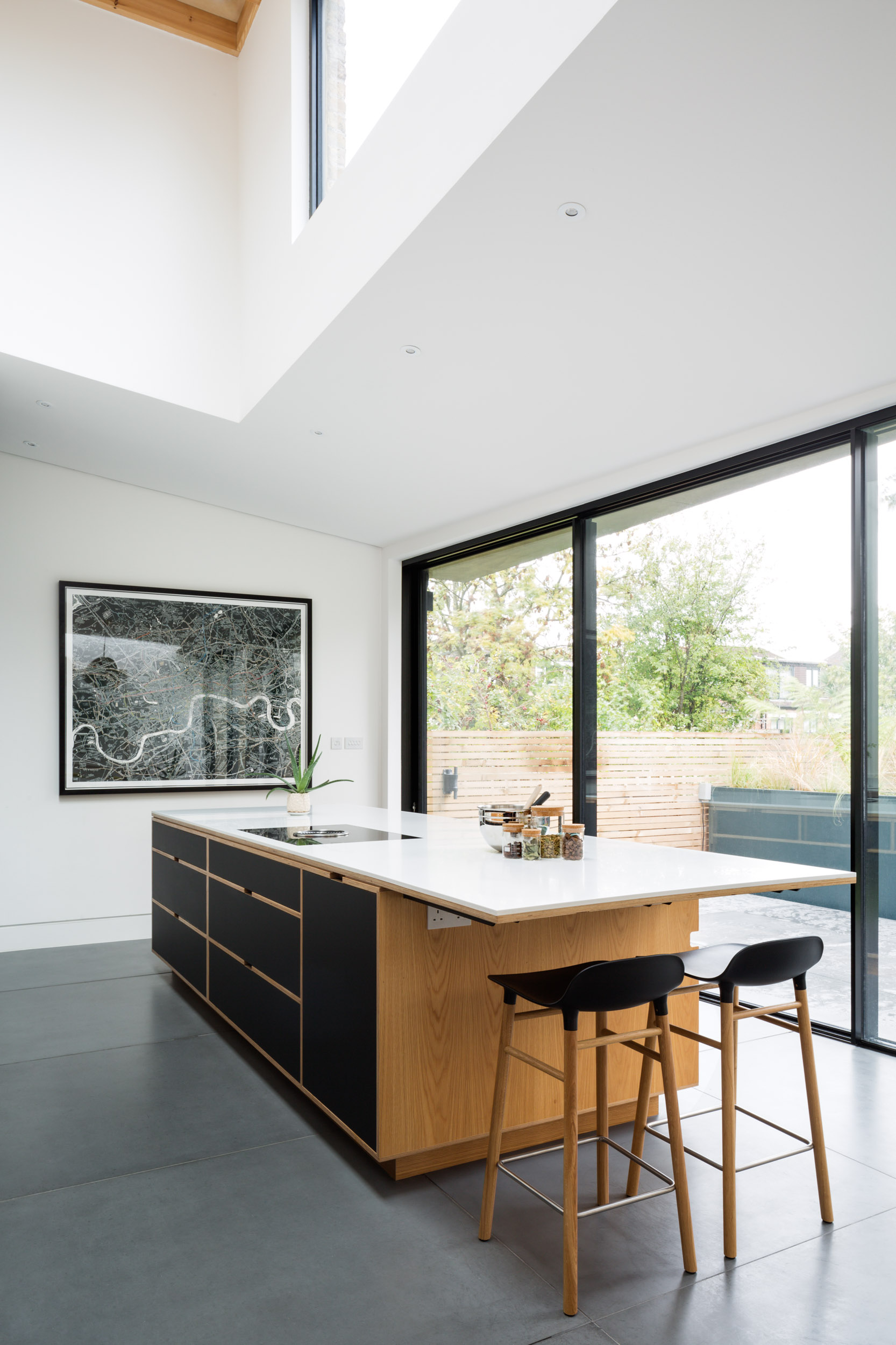 oak and plywood kitchen island in double height space. Garden behind.