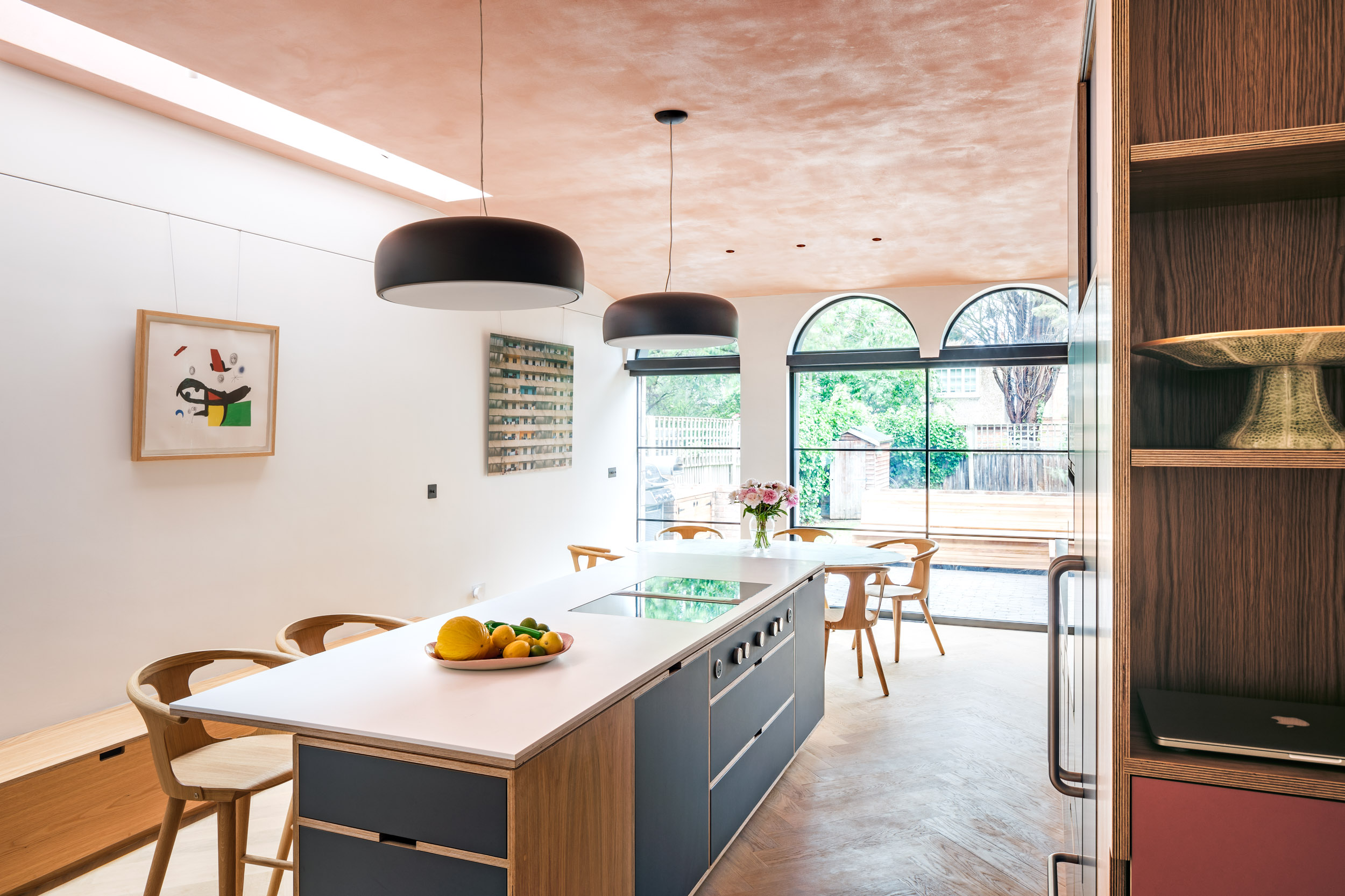 Bespoke oak plywood kitchen and island in Dulwich. Pink plaster ceiling. Arched glazing to garden.