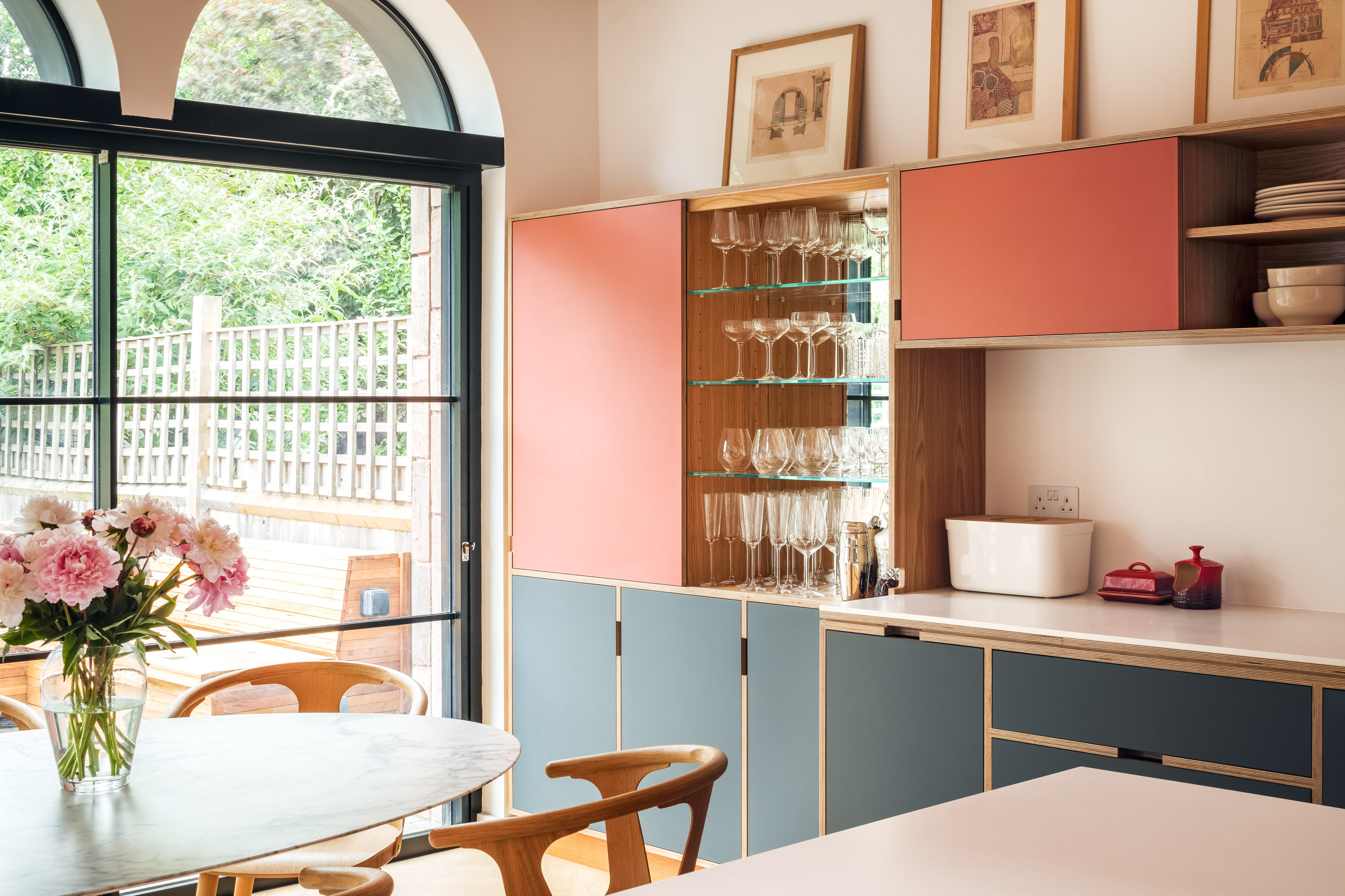 Drinks cabinet and kitchen integrated storage. in oak, pink and grey.. With table and arched doors to garden.