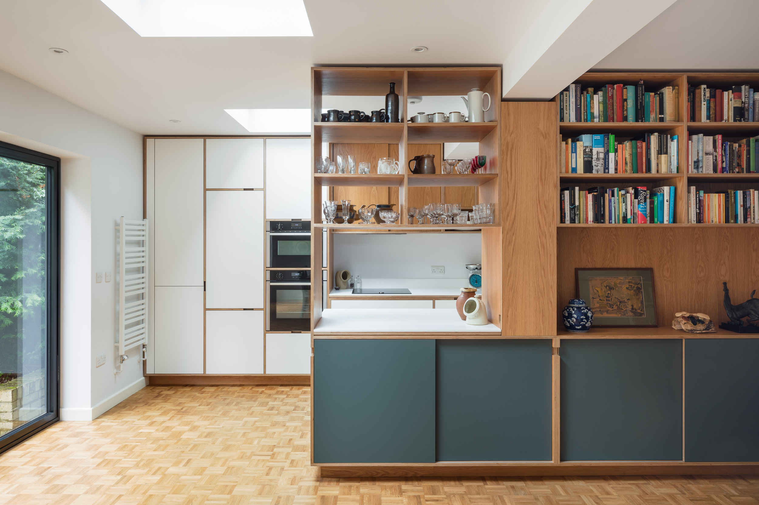 Open plywood bookcase with kitchen behind
