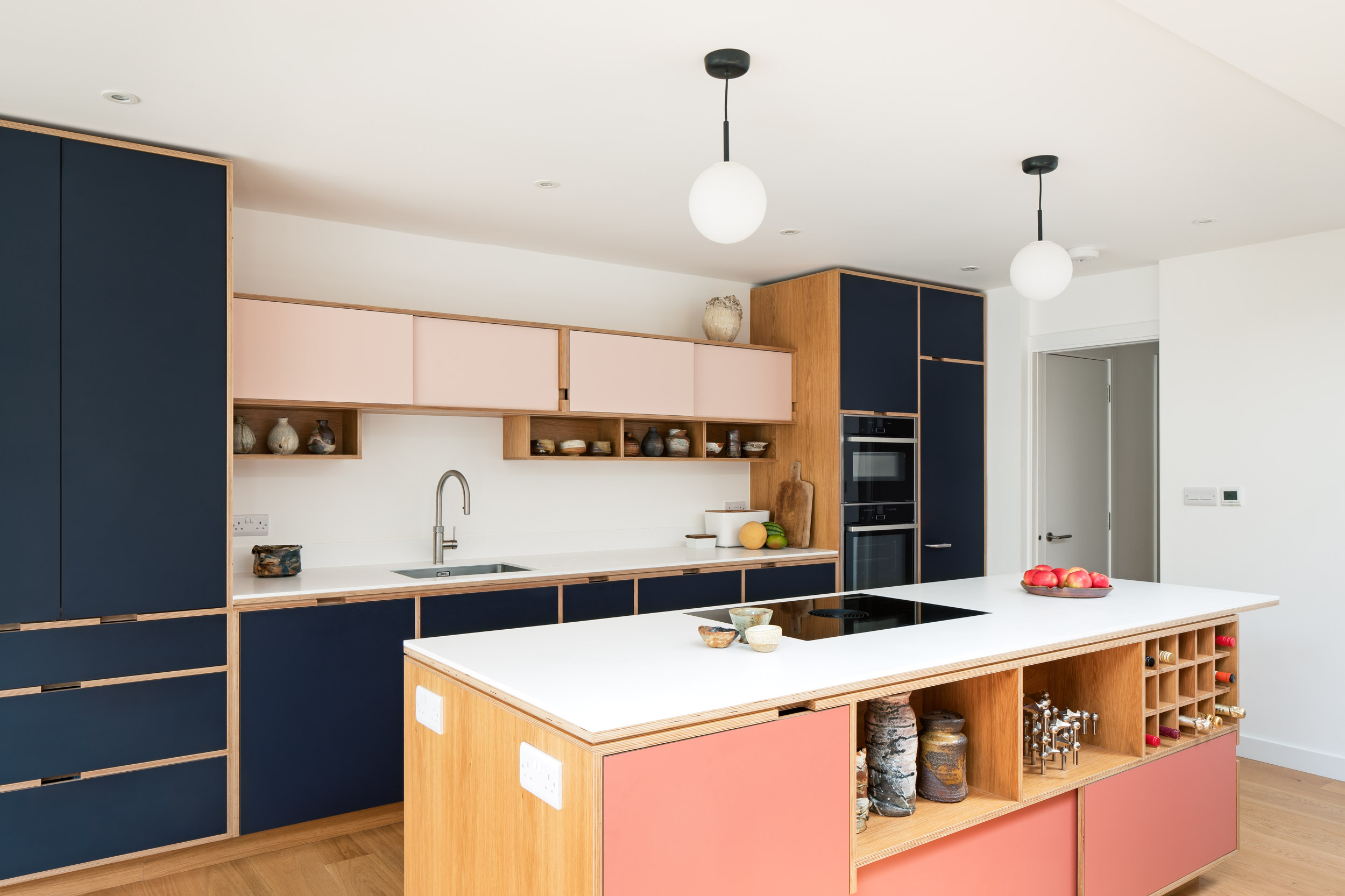 Modern, warm pink and midnight blue plywood kitchen with island