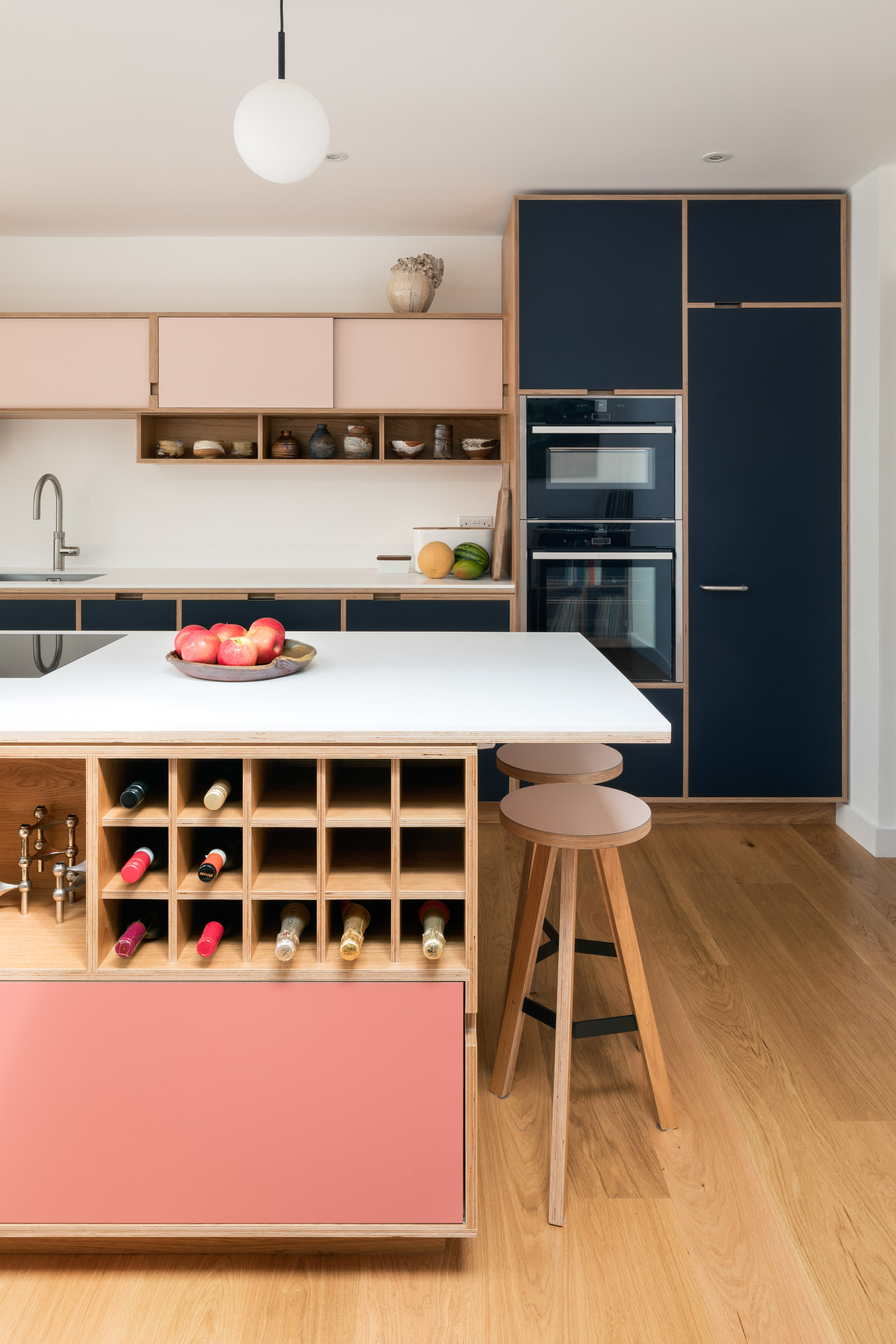 Pink and midnight blue plywood kitchen island with integrated wine rack