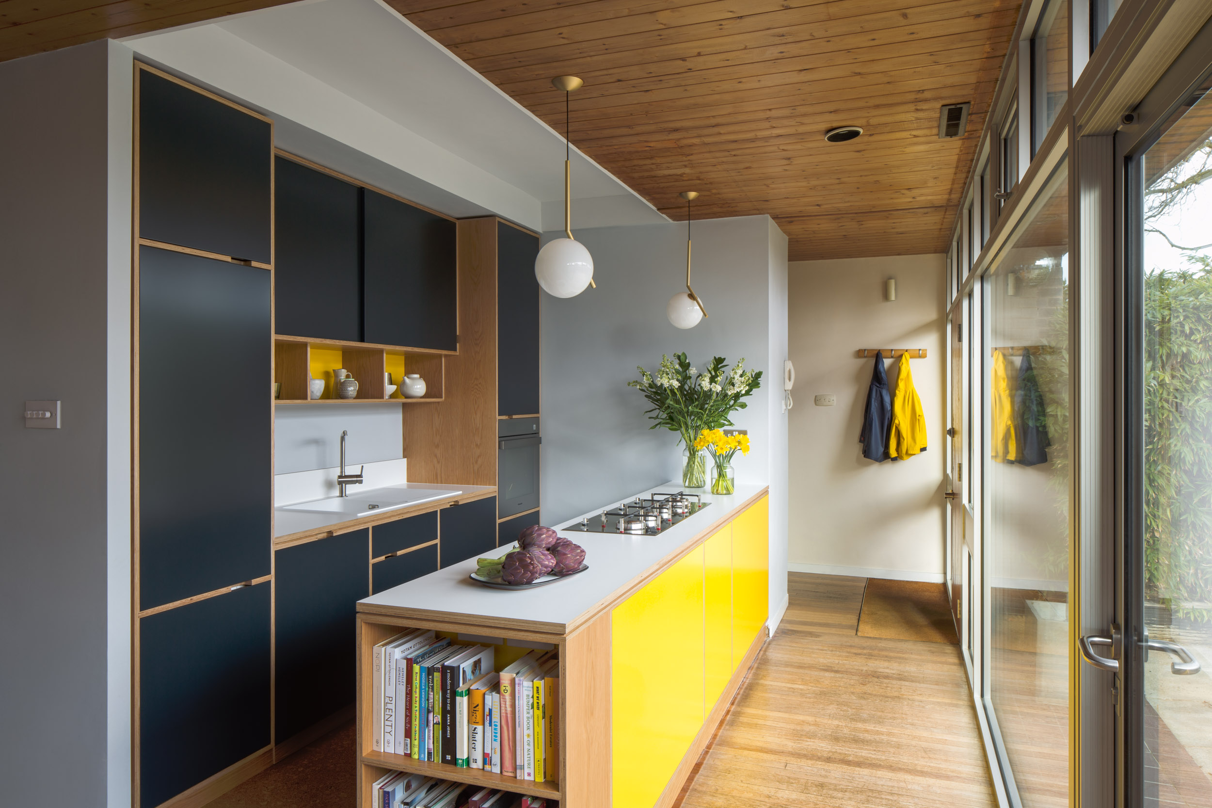 Yellow peninsual with bookcase on the end. Dark grey doors
