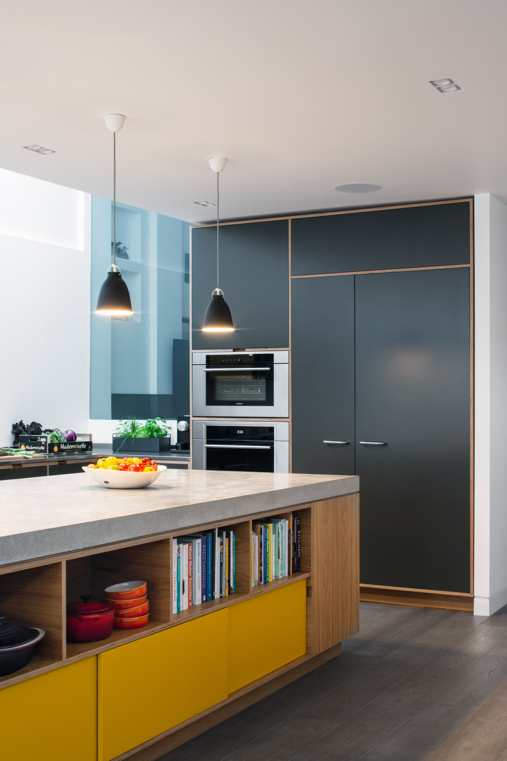 Plywood and concrete island with yellow doors and open shelving
