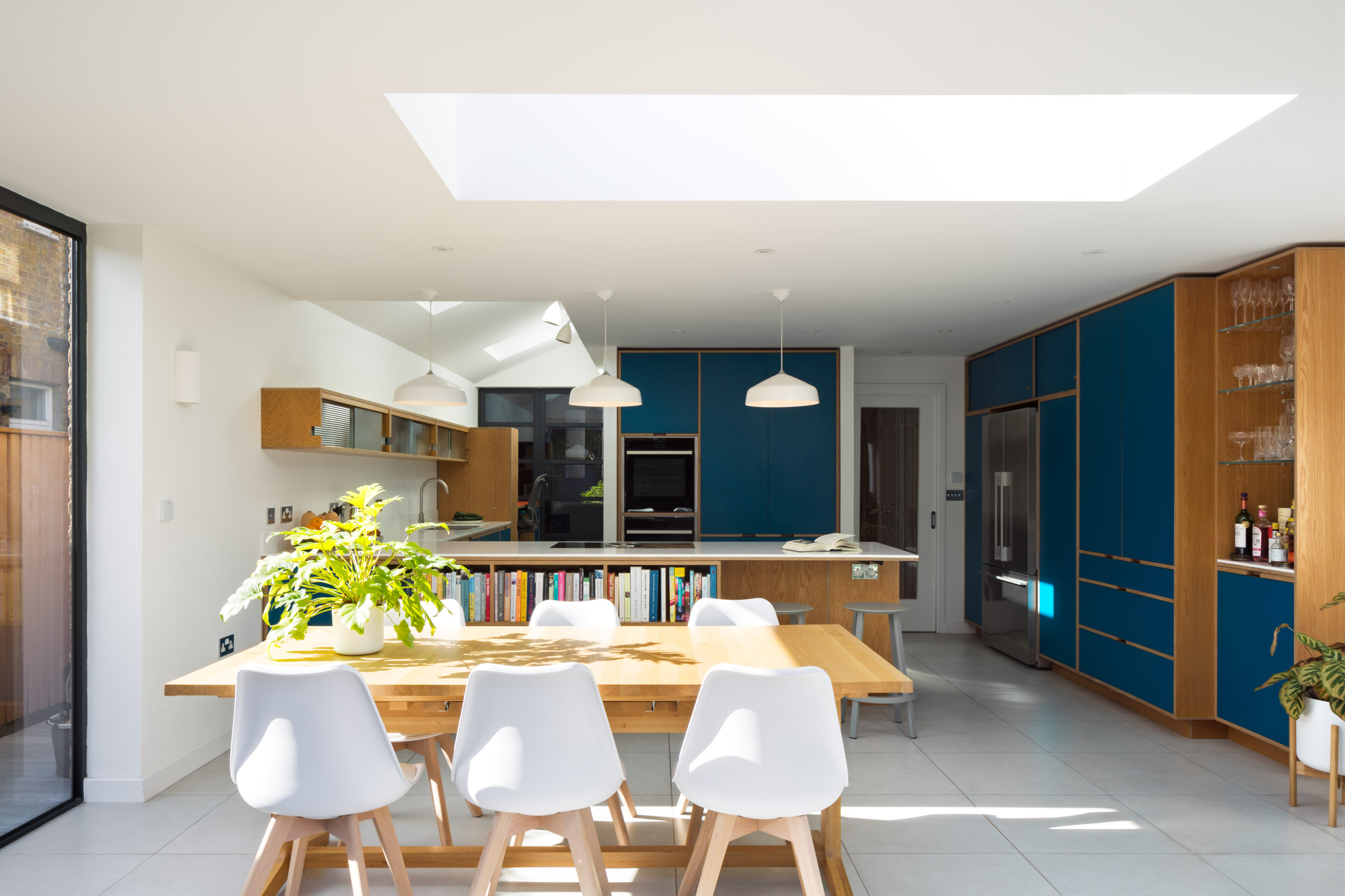 Bespoke plywood kitchen in teal and oak. With dining table in the foreground