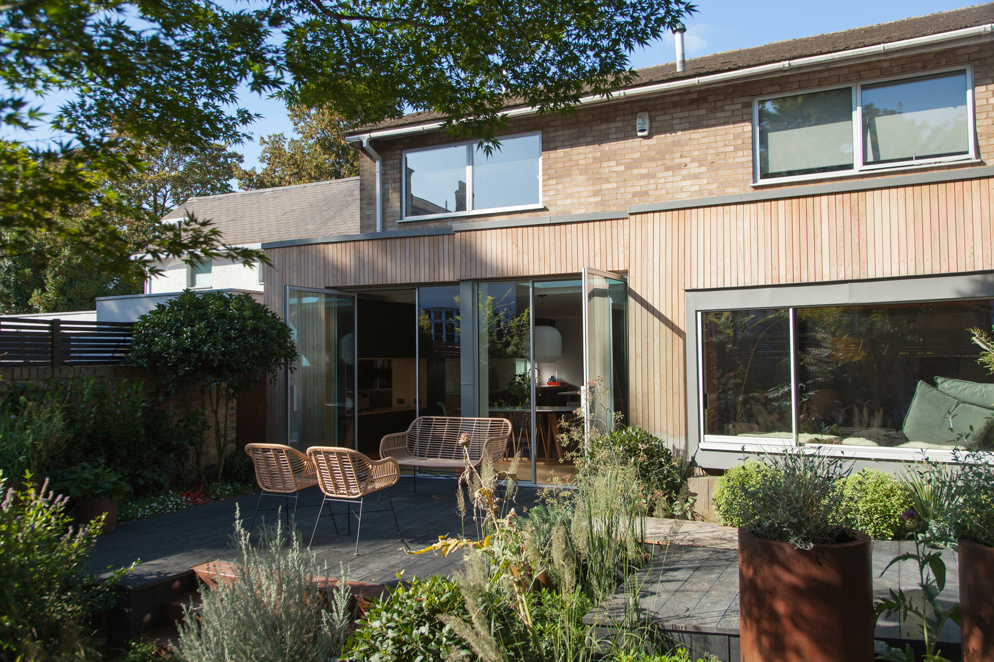 Wooden slated extension looking in on a plywood kitchen