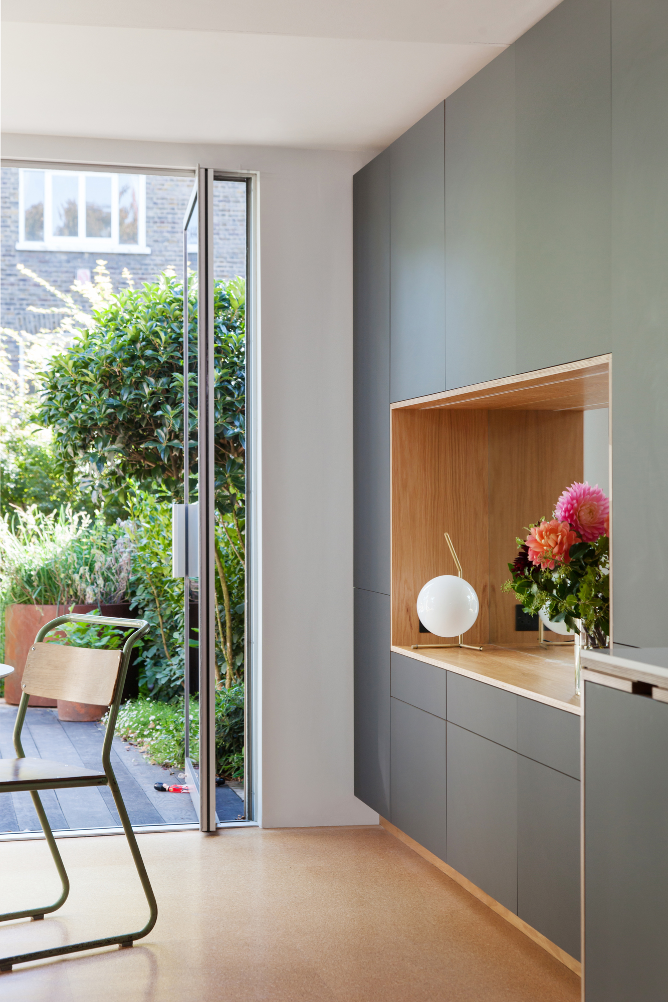 Looking out to a lush garden past black door plywood storage