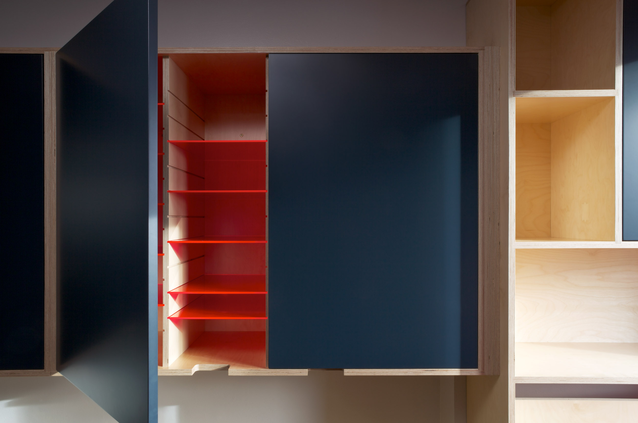 Blue Plywood storage with neon red acrylic shelving