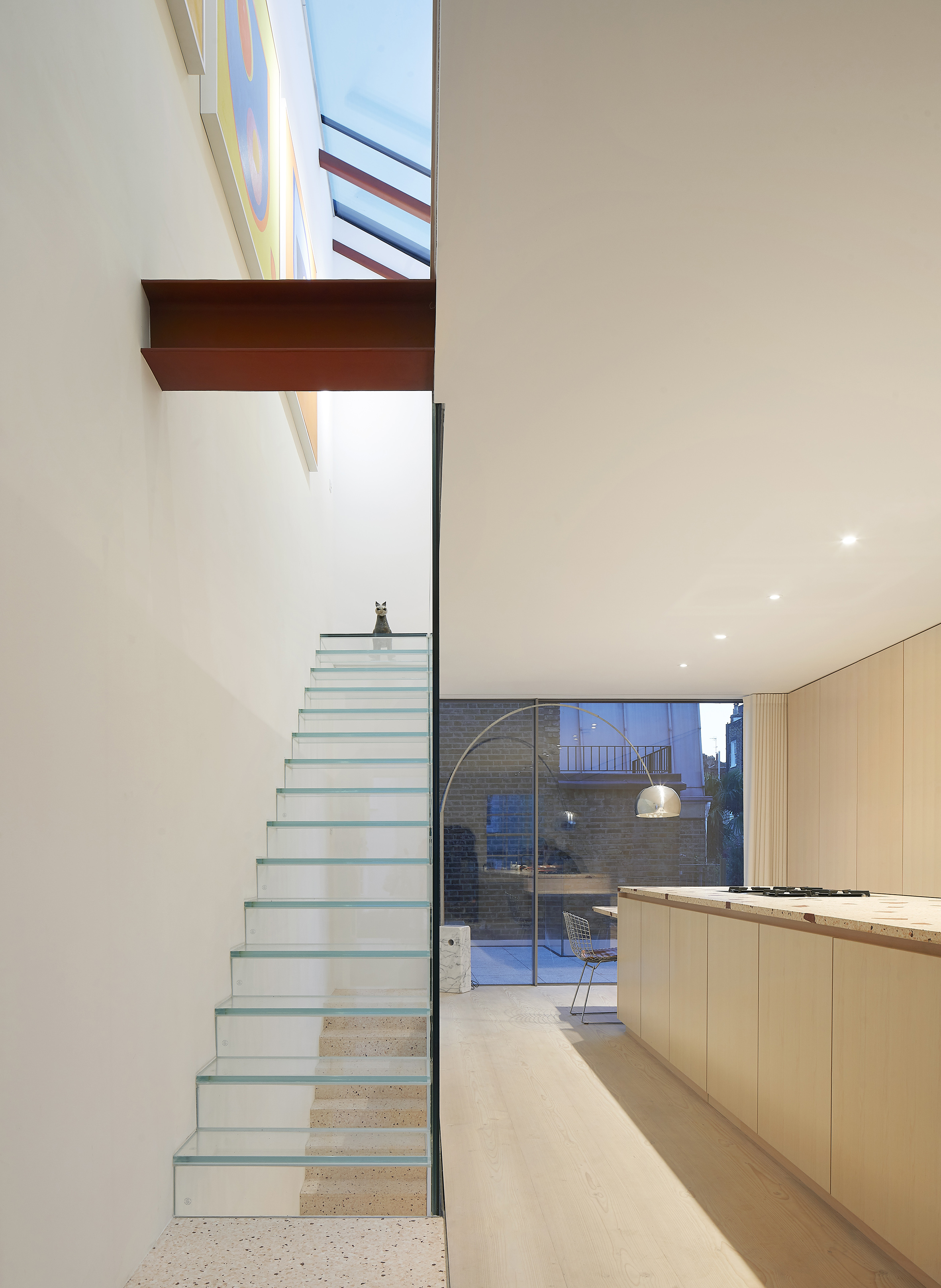 Glass staircase with plywood kitchen to one side