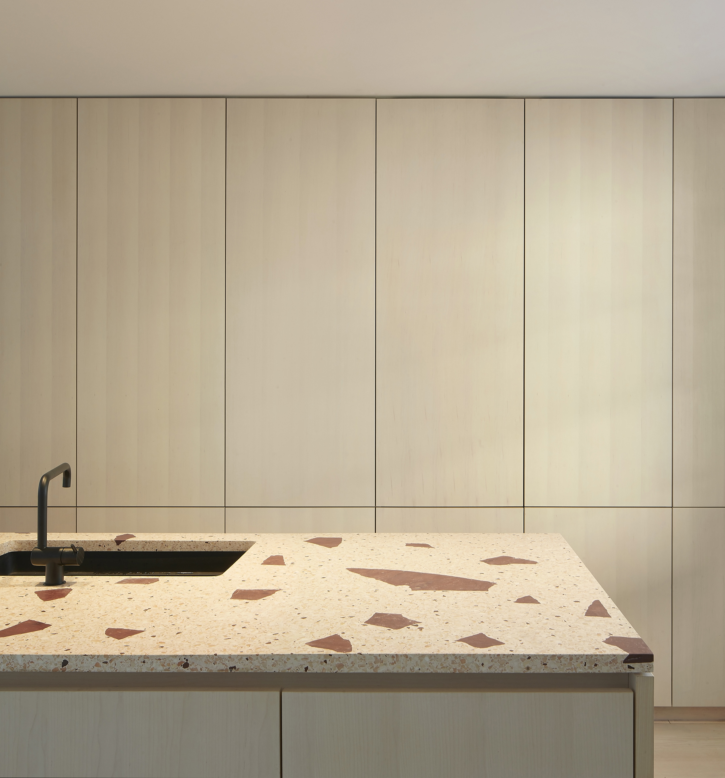 Characterful terrazzo island with wood veneer cabinetry behind