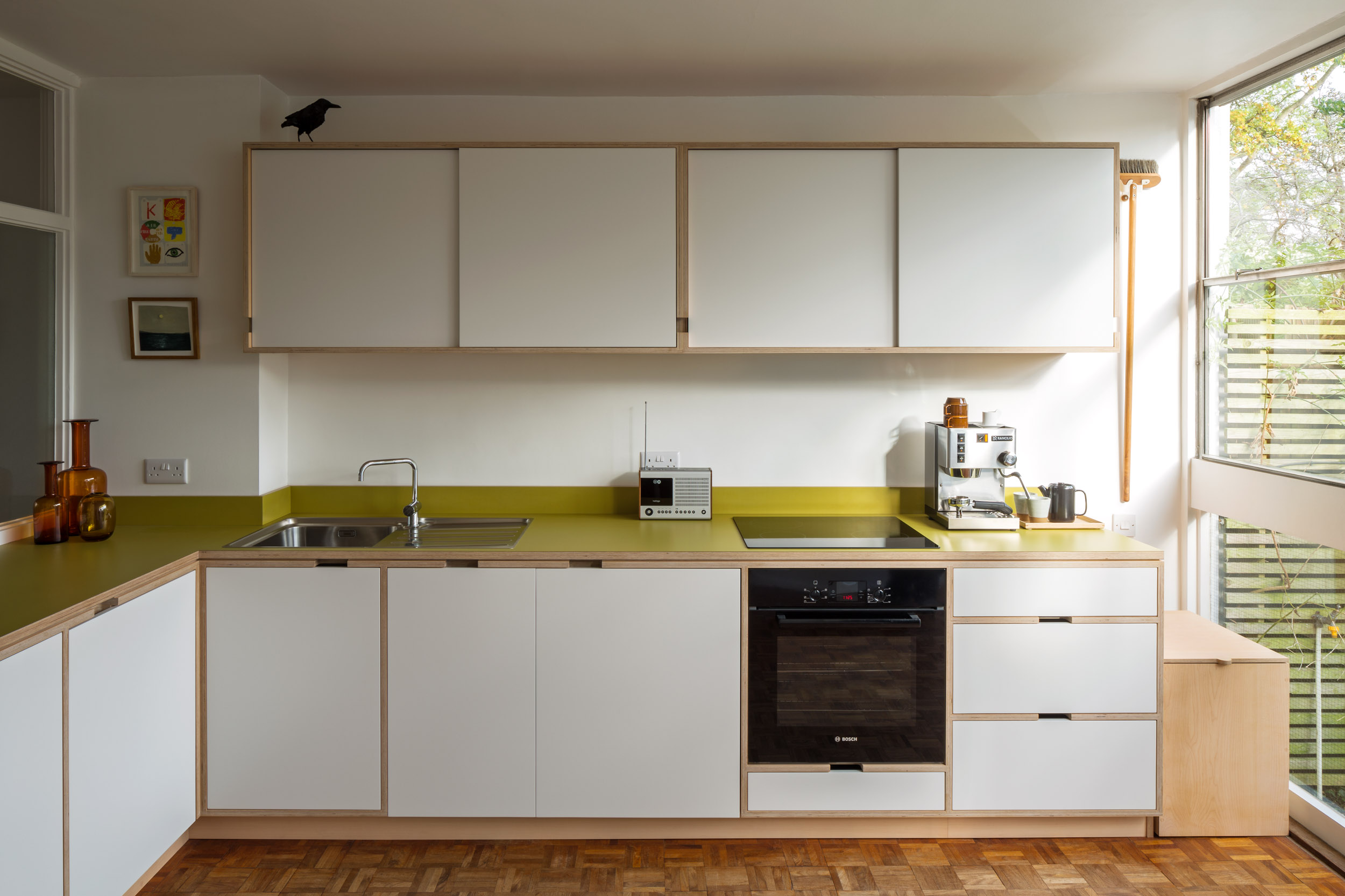 Classic span house kitchen. Bespoke plywood, laminate and herringbone parquet flooring. White kitchen doors