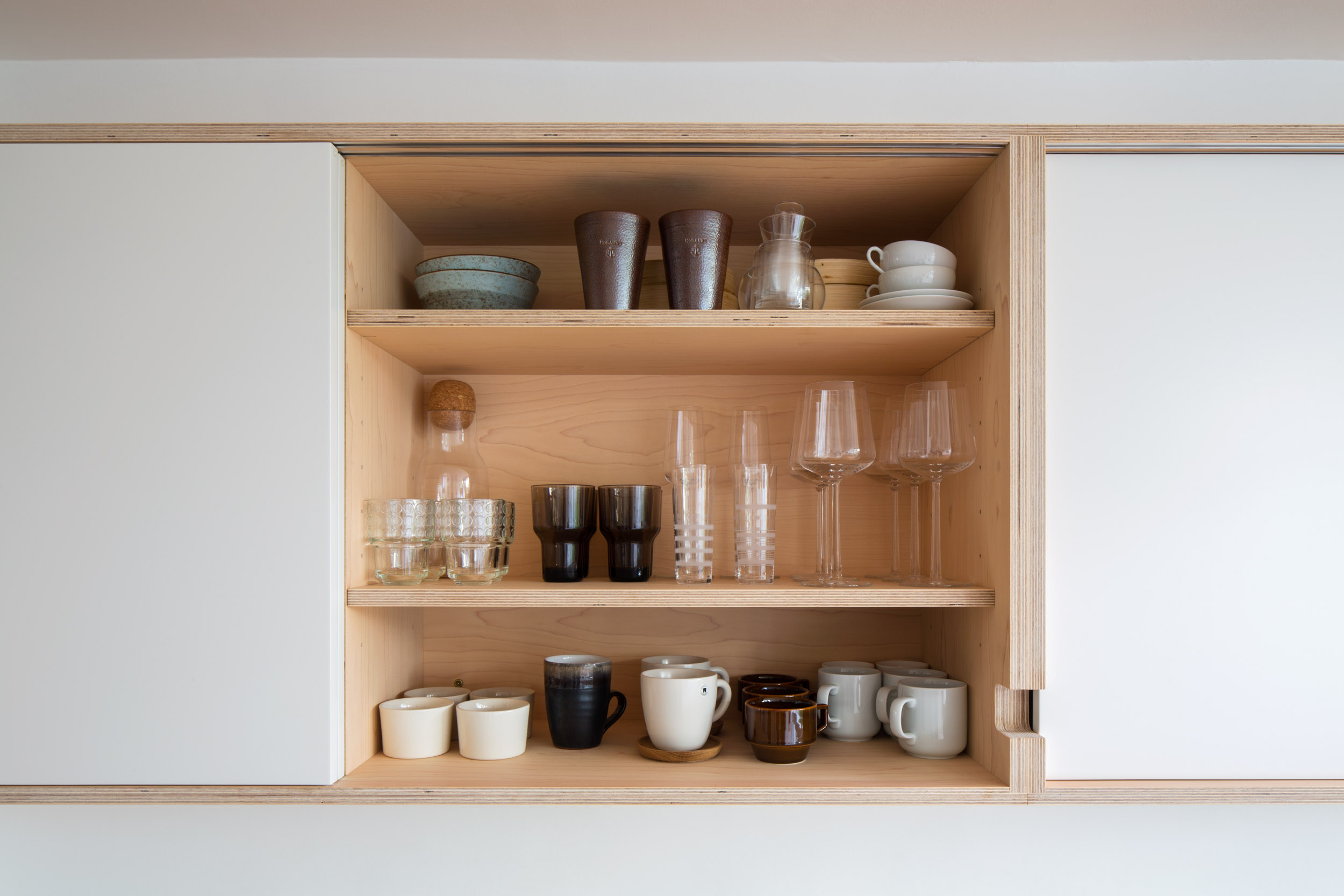 Plywood wall cabinet with white sliding doors.