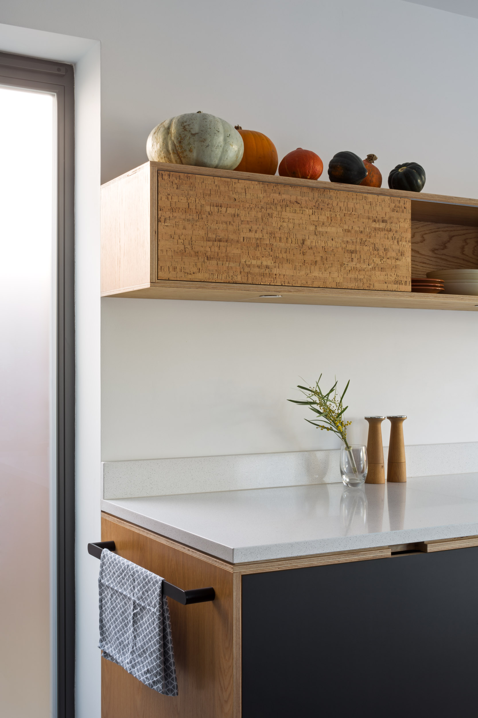Large bank of black full height kitchen cabinetry including pantry cupboard with pocket doors