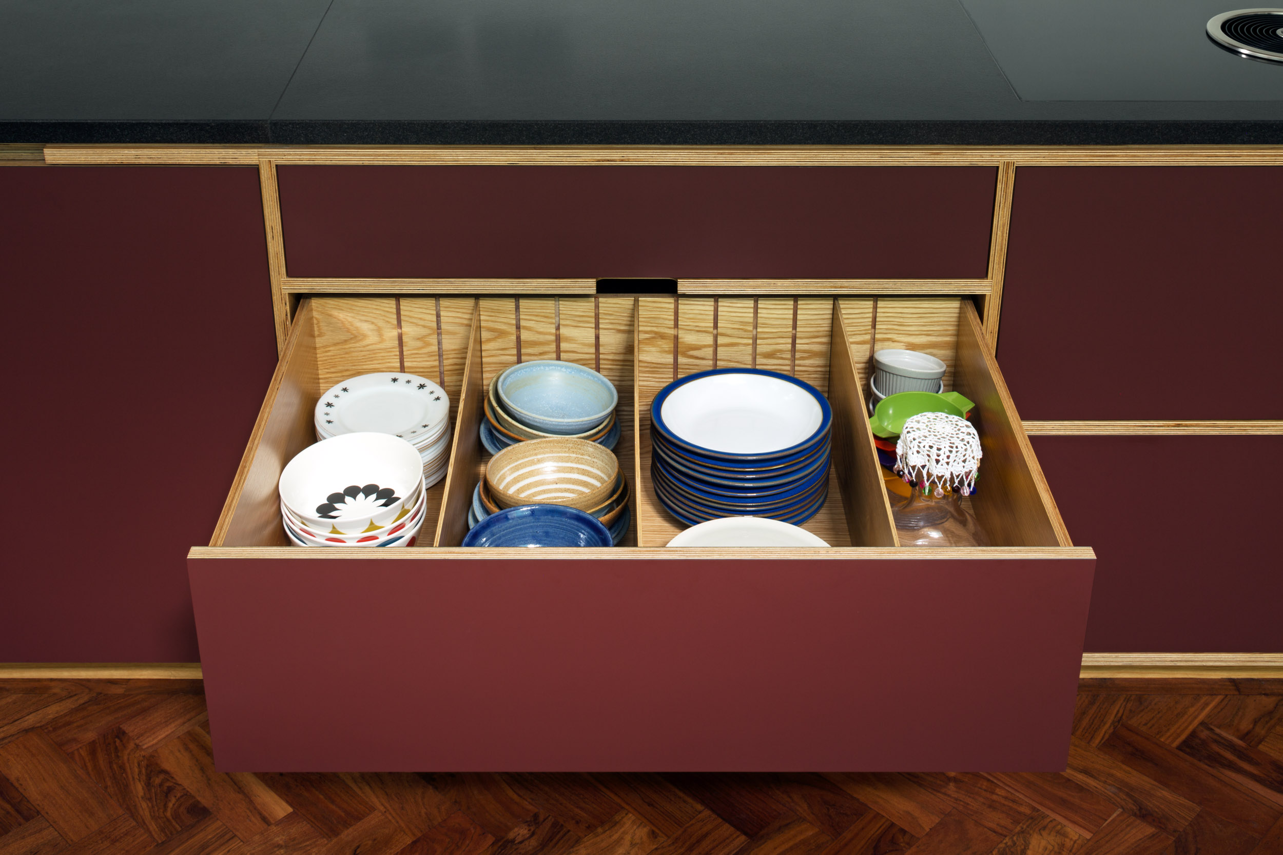 Slate worktop and maroon cupboard with open storage drawer