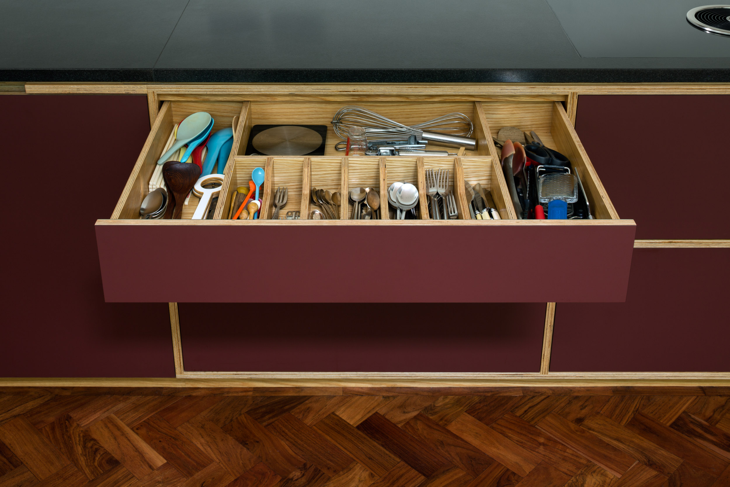 Slate worktop and maroon cupboard with open cutlery drawer