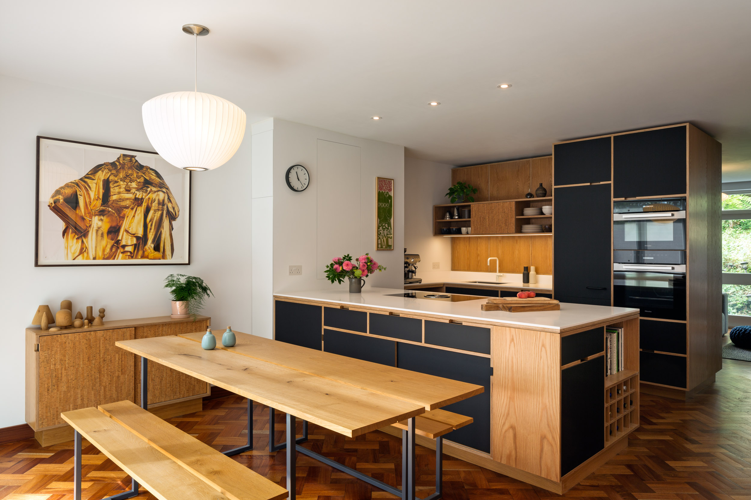 Plywood kitchen with table and bench seats in foreground