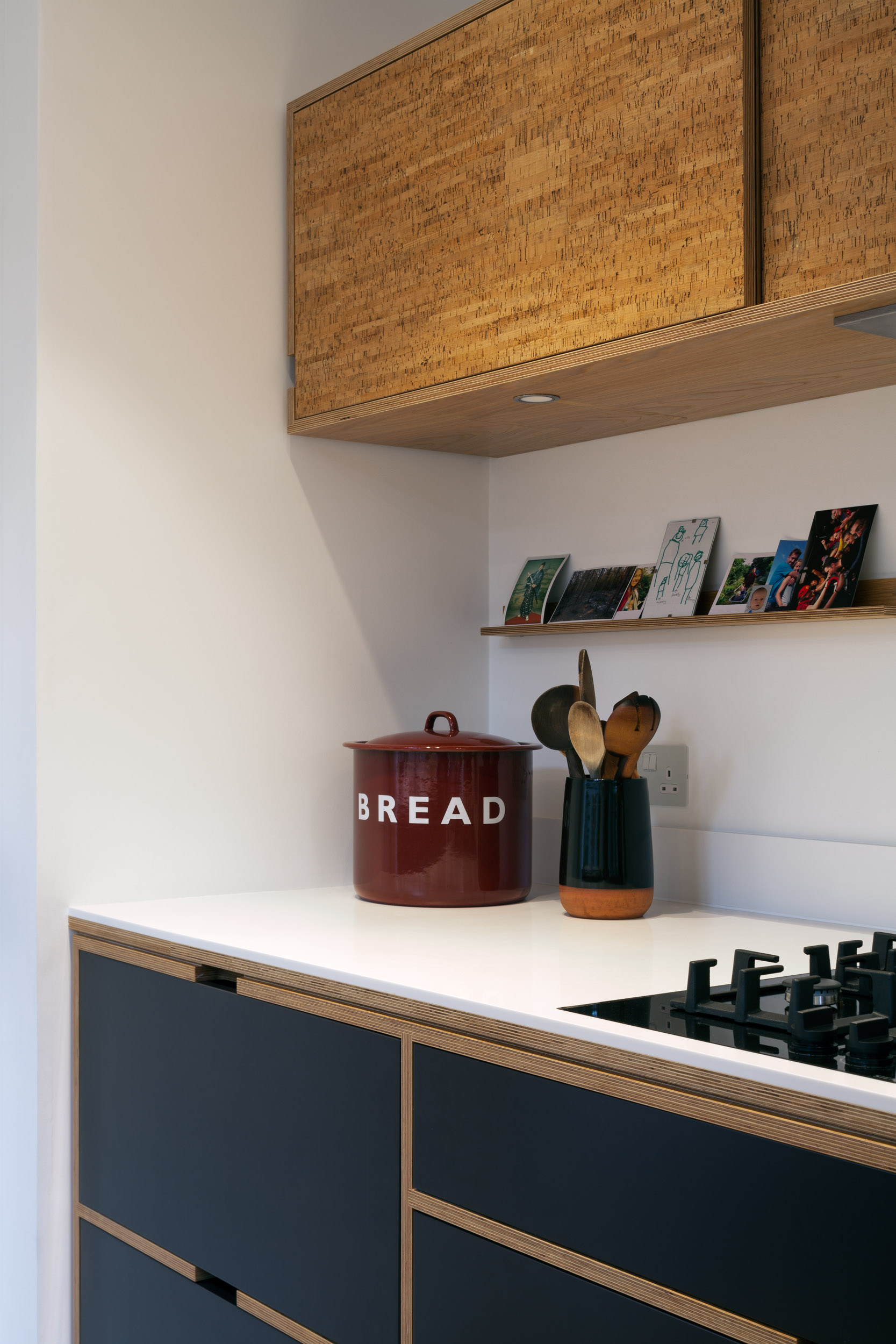 Linear cork, black doors and plywood kitchen cabinets