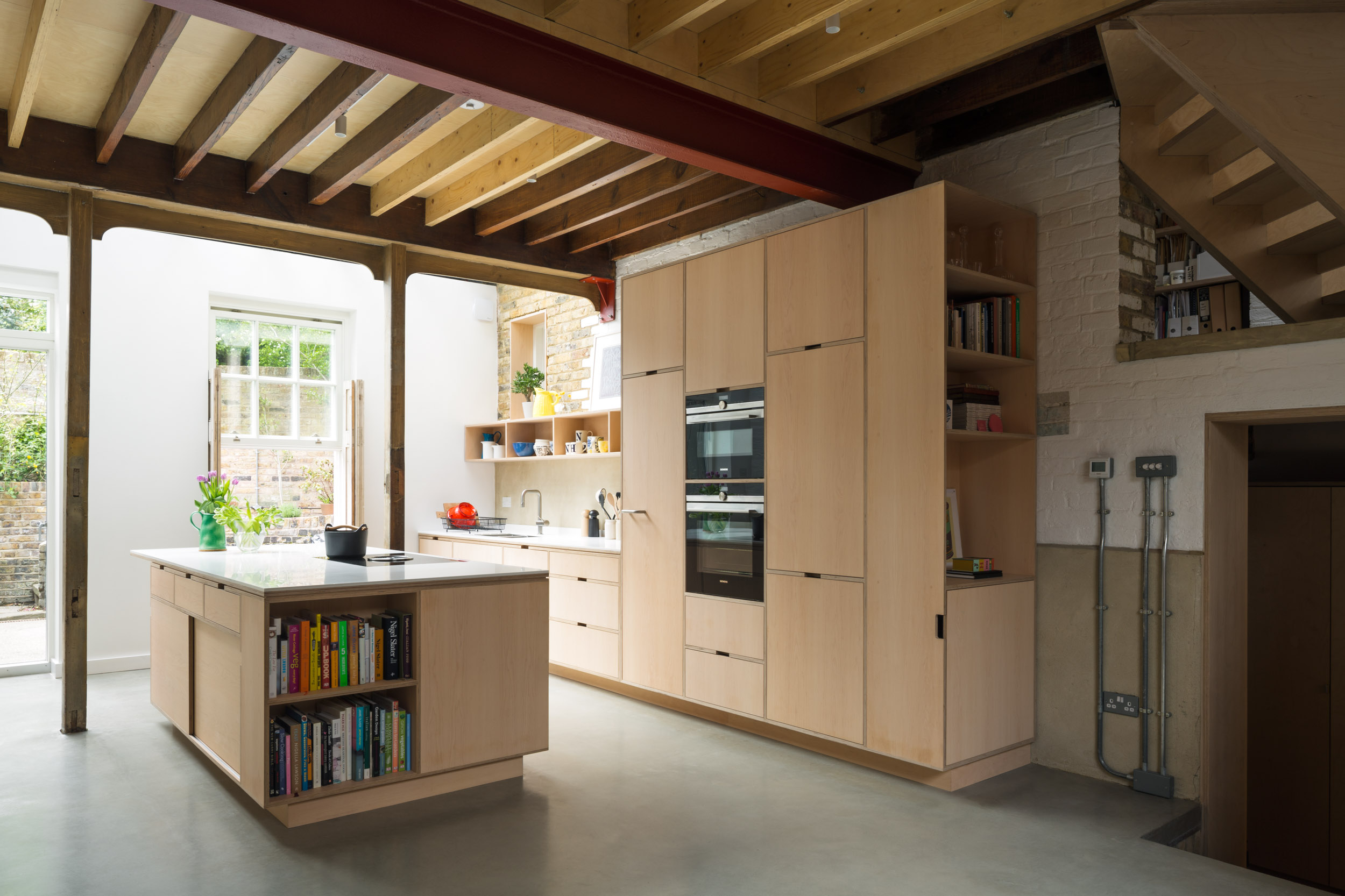 Maple veneered plywood kitchen in a coach house with exposed beams