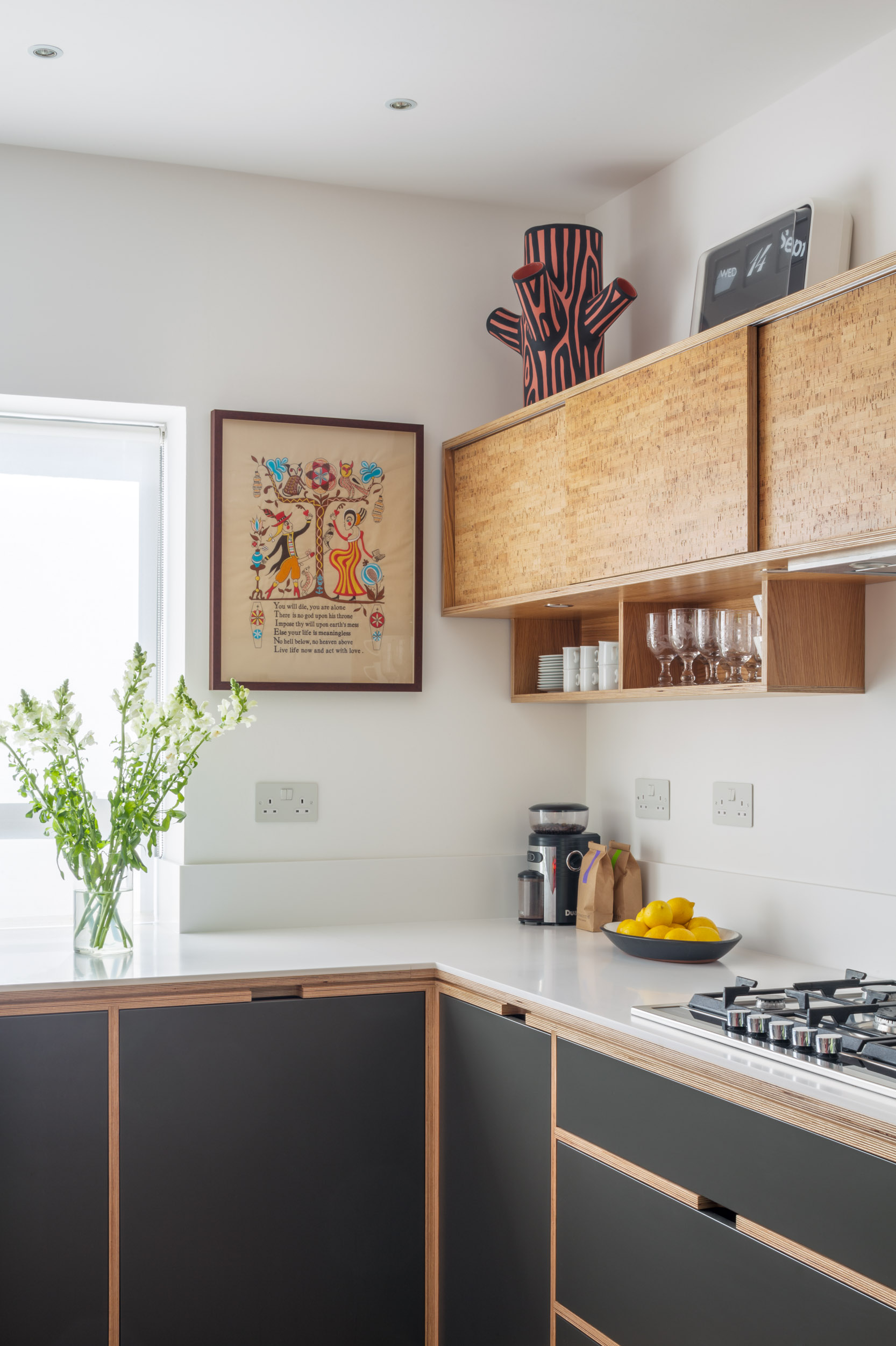 Detail of dark grey plywood kitchen with narrow cork wall units
