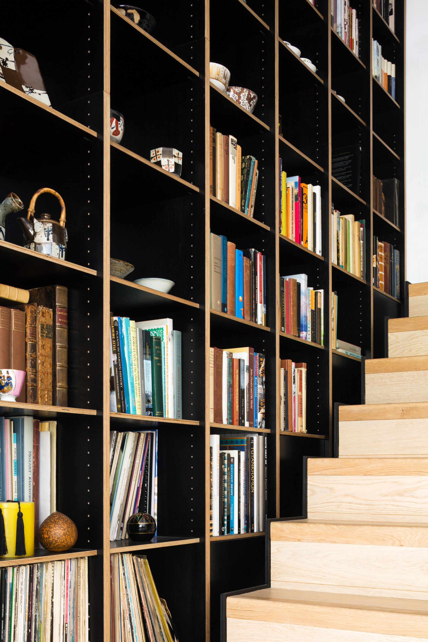 Dyed black veneer ply shelving over staircase