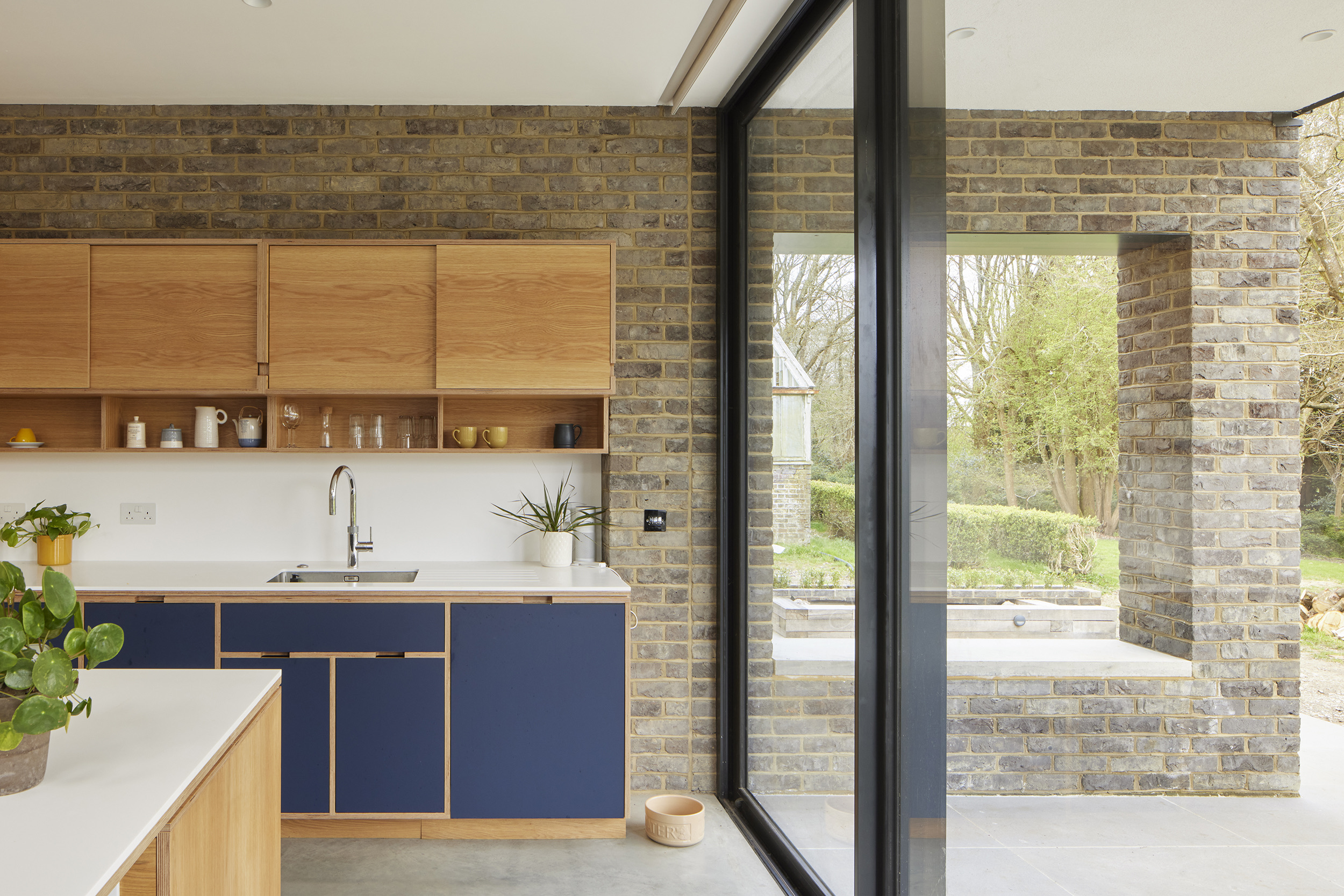Spacious open-plan kitchen and dining extension by Uncommon Projects with bespoke plywood island, polished concrete floors and panoramic garden glazing. Architecture by Selencky Parsons.