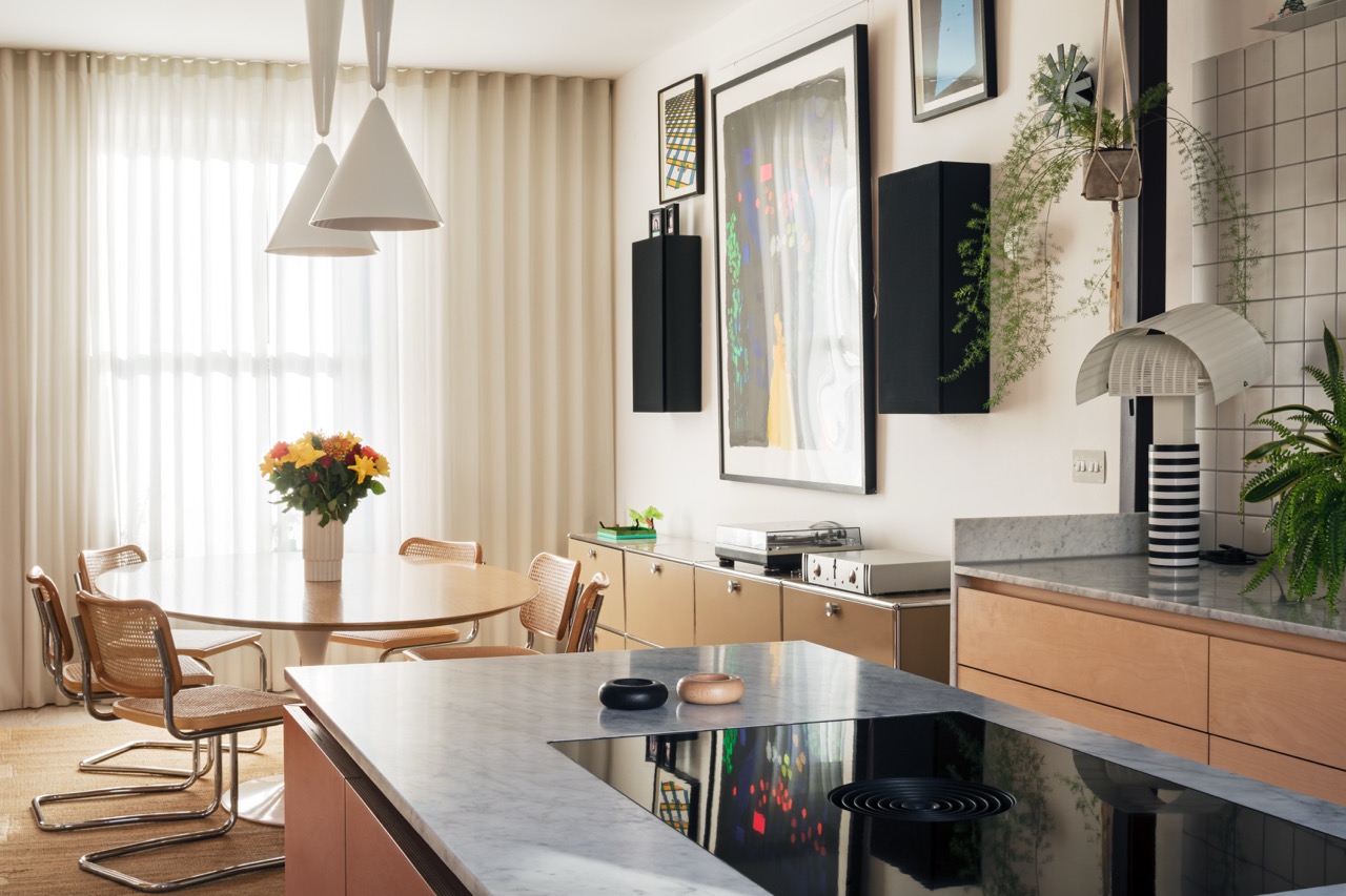 View across kitchen island with induction hob to bespoke ply maple veneer kitchen and dining area, Hackney