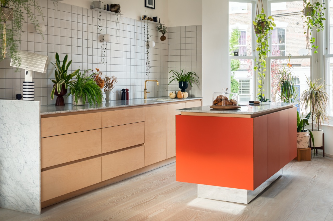 Orange kitchen island with marble worktop beside maple veneer base units, bespoke plywood kitchen Hackney