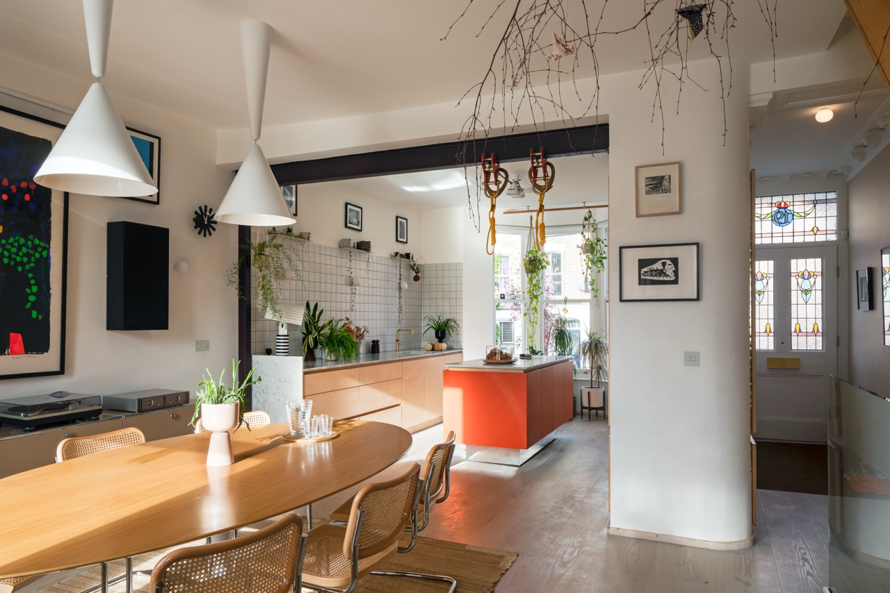Open-plan kitchen and dining room with orange kitchen island, bespoke plywood kitchen Hackney by Uncommon Projects