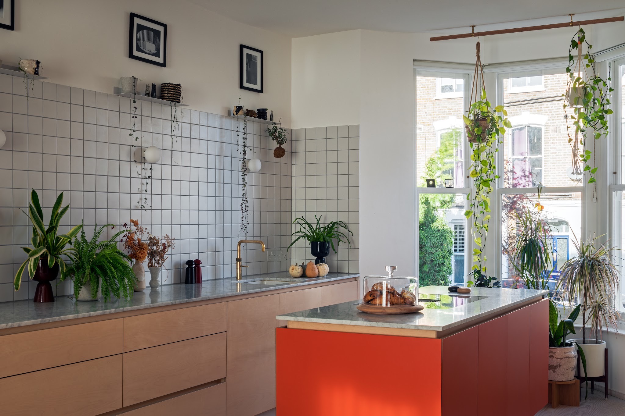 Kitchen by Archmongers with bespoke plywood cabinetry by Uncommon Projects, marble worktops, white tiles and a red island.