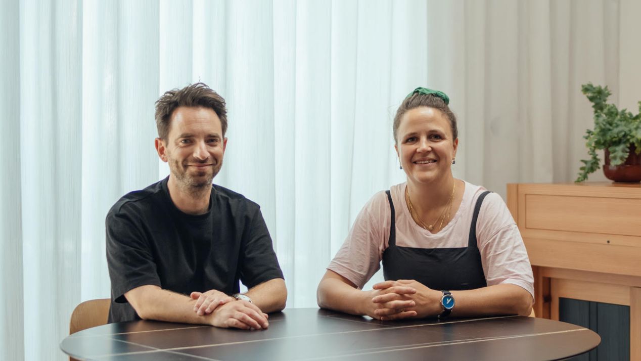     Archmongers founders Johan Hybschmann and Margaret Bursa seated together at a table in a contemporary interior.